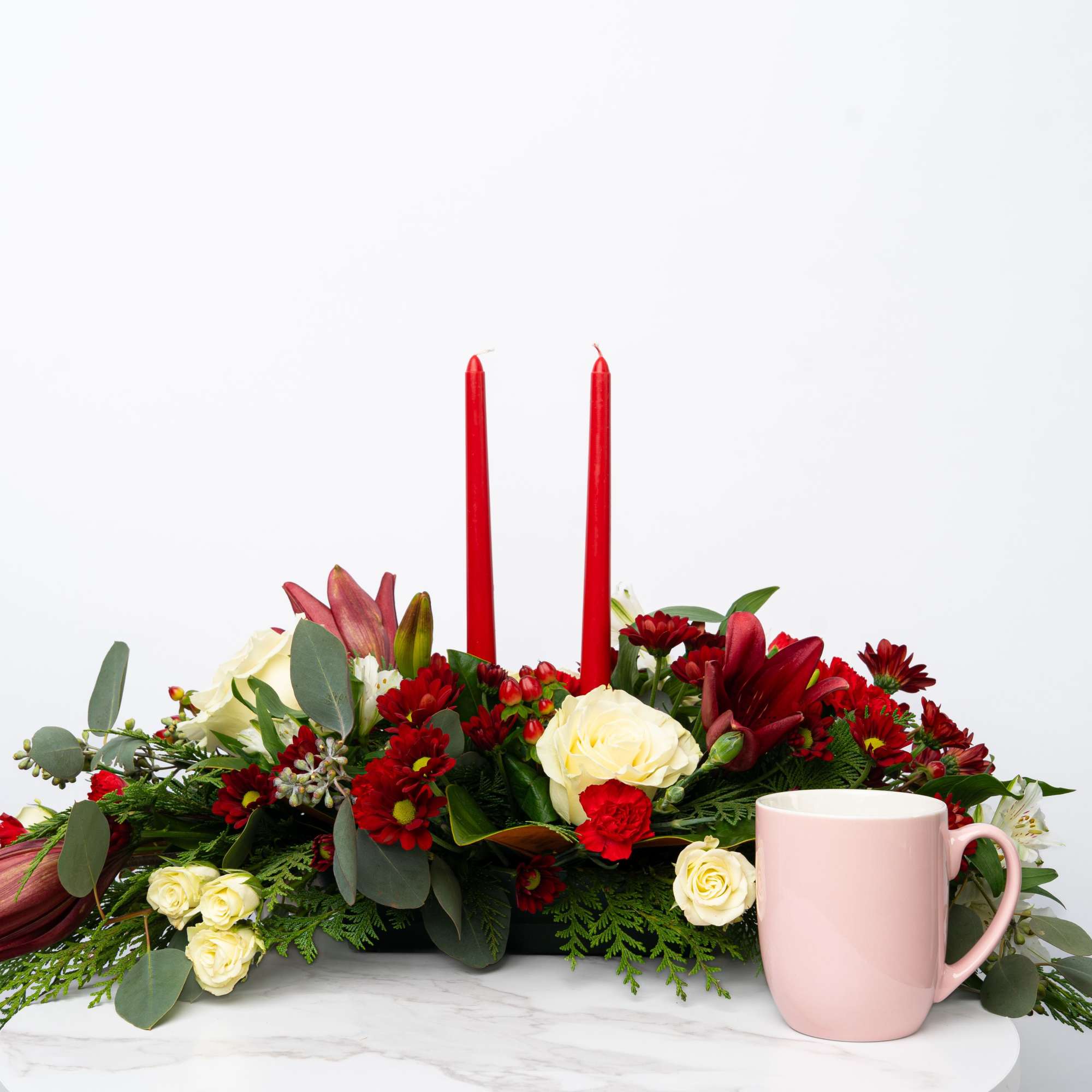 Red and cream floral centerpiece with two red candles and a pink mug