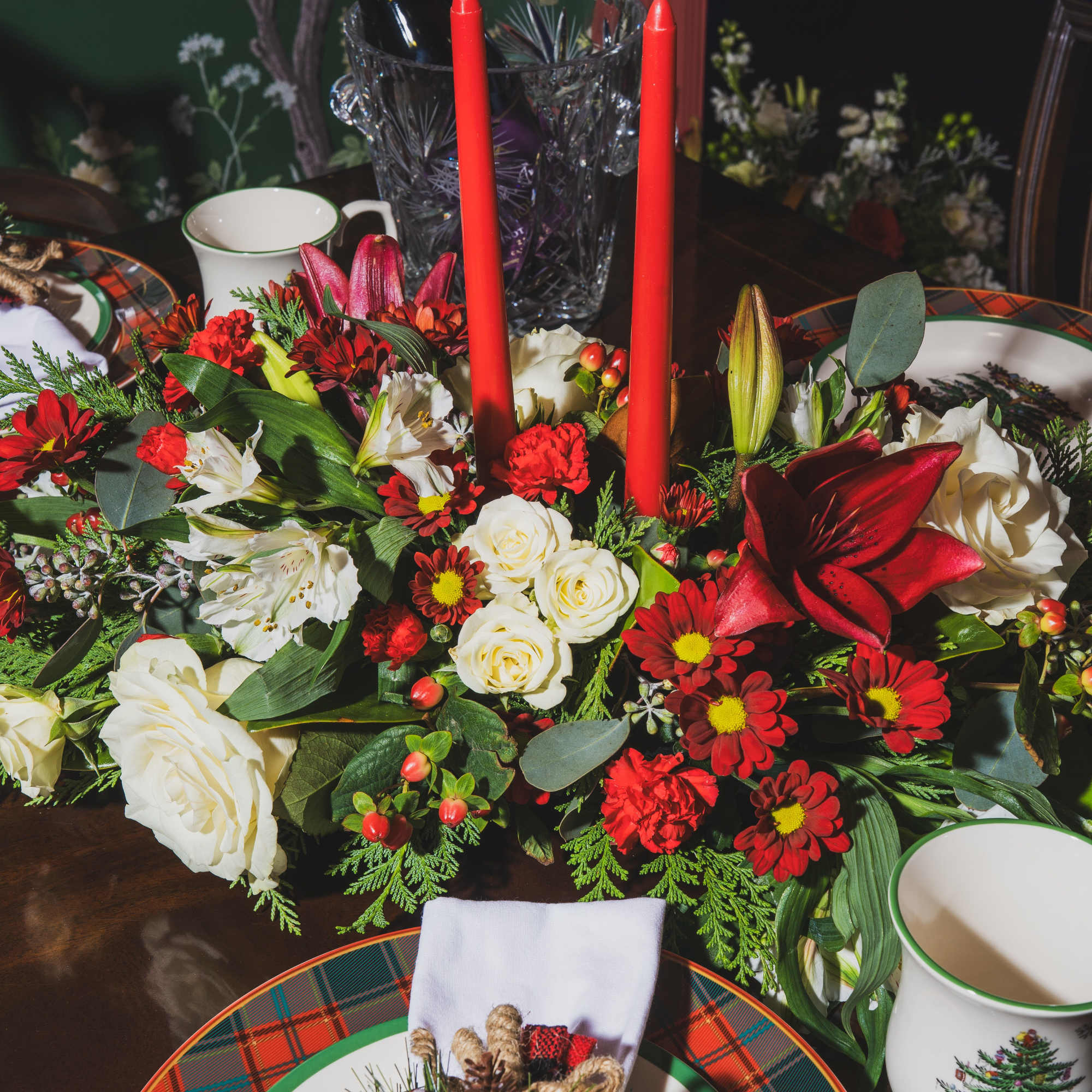 Holiday table centerpiece with red candles and mixed flowers