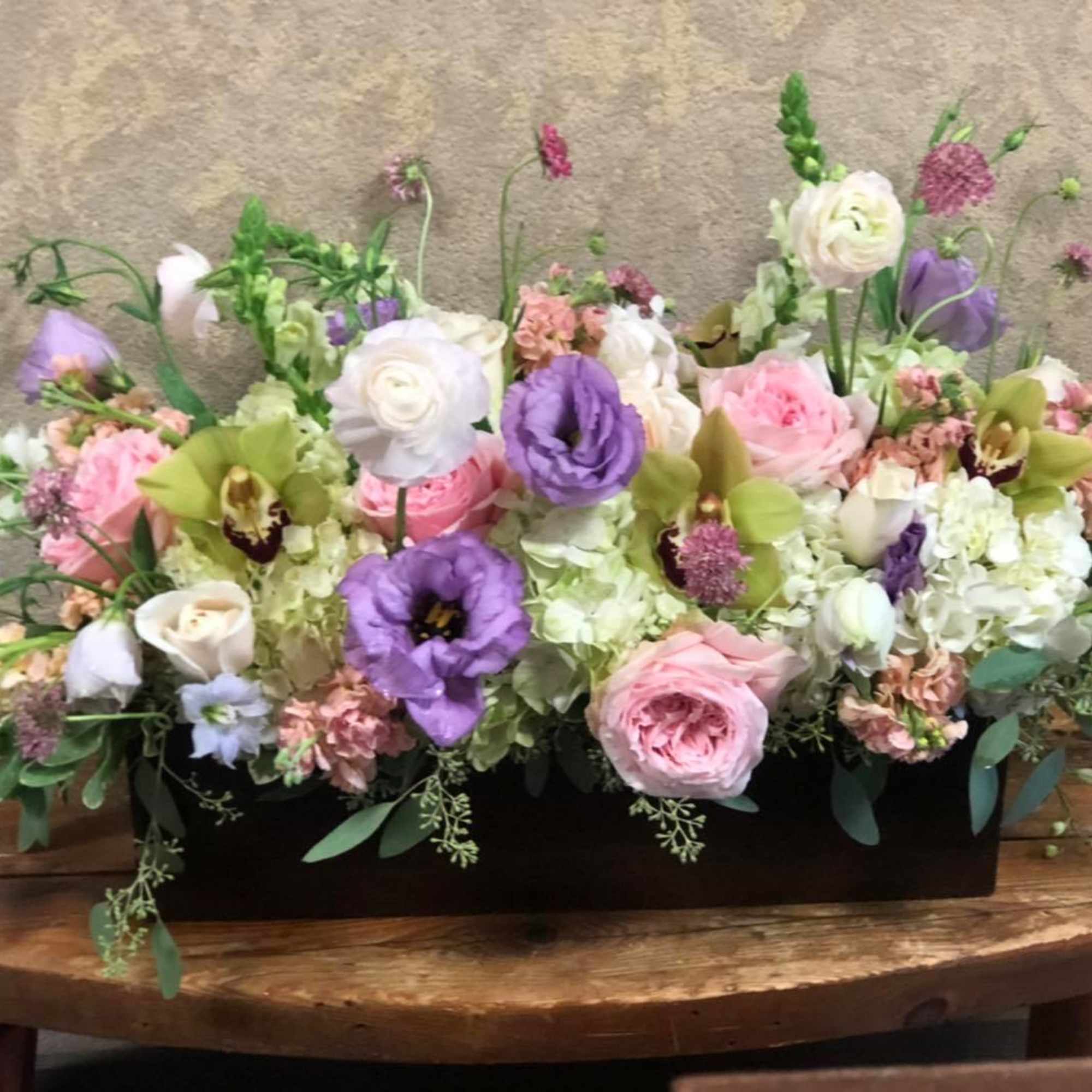 Low floral centerpiece with pink, white, and purple blooms in a black container