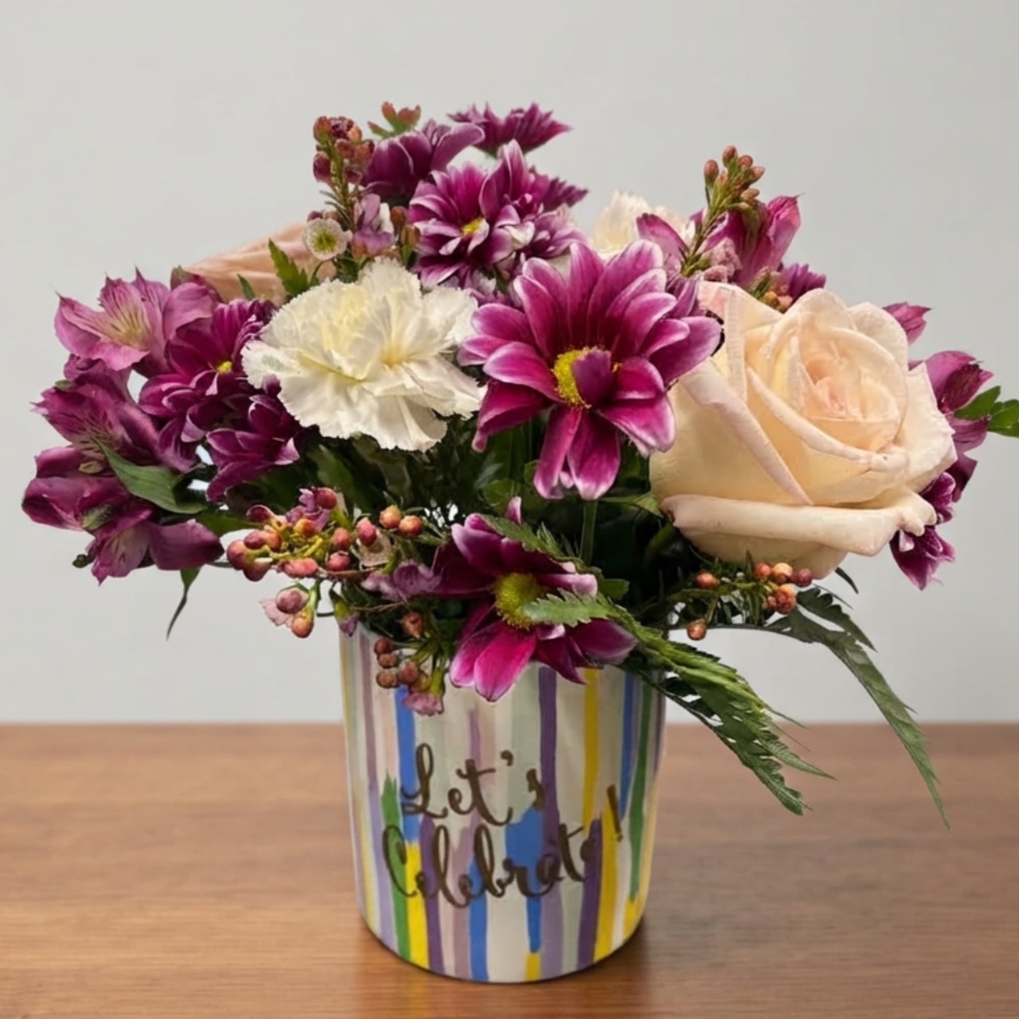 Purple and cream flowers arranged in a striped vase