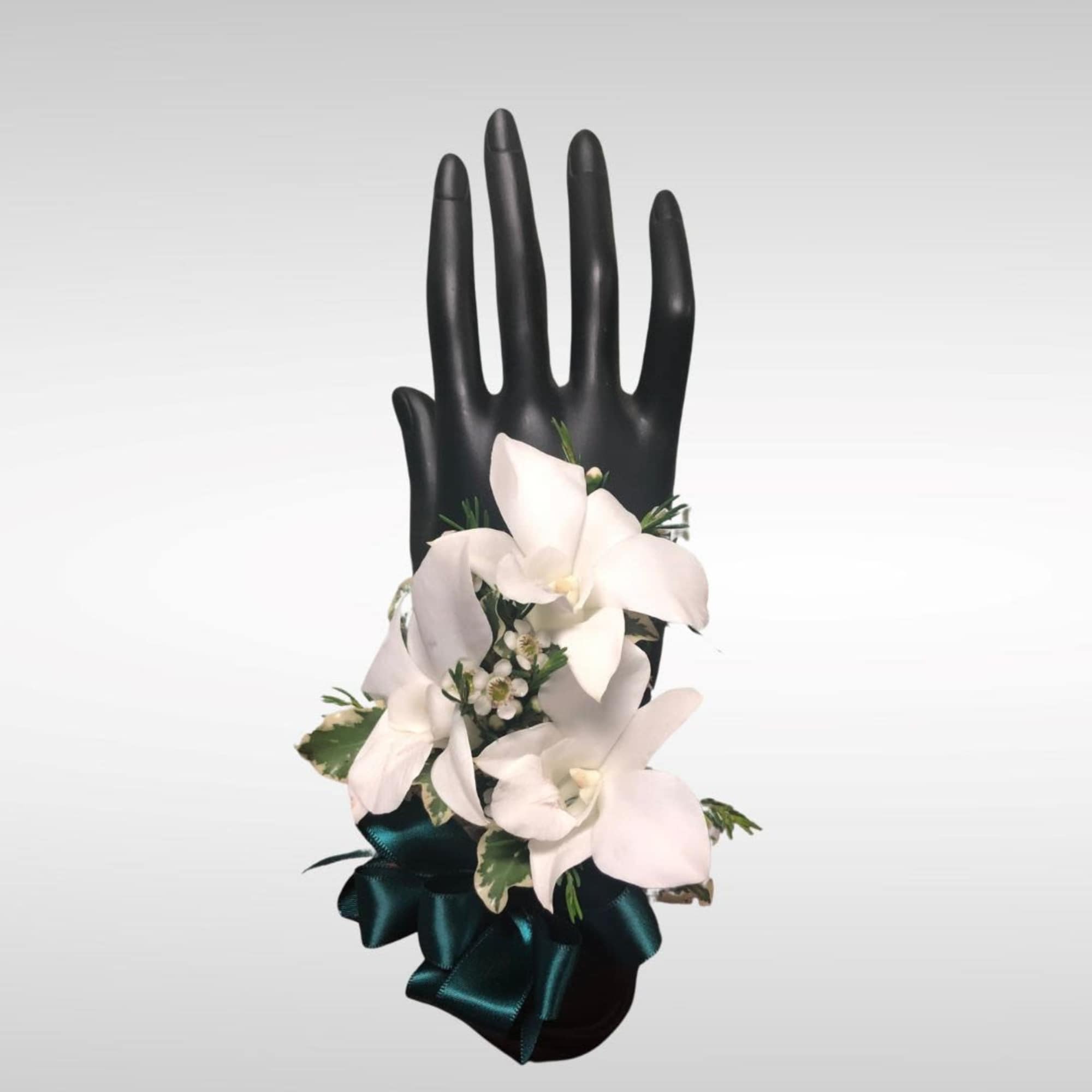 White flowers arranged on a black hand-shaped display with a teal ribbon