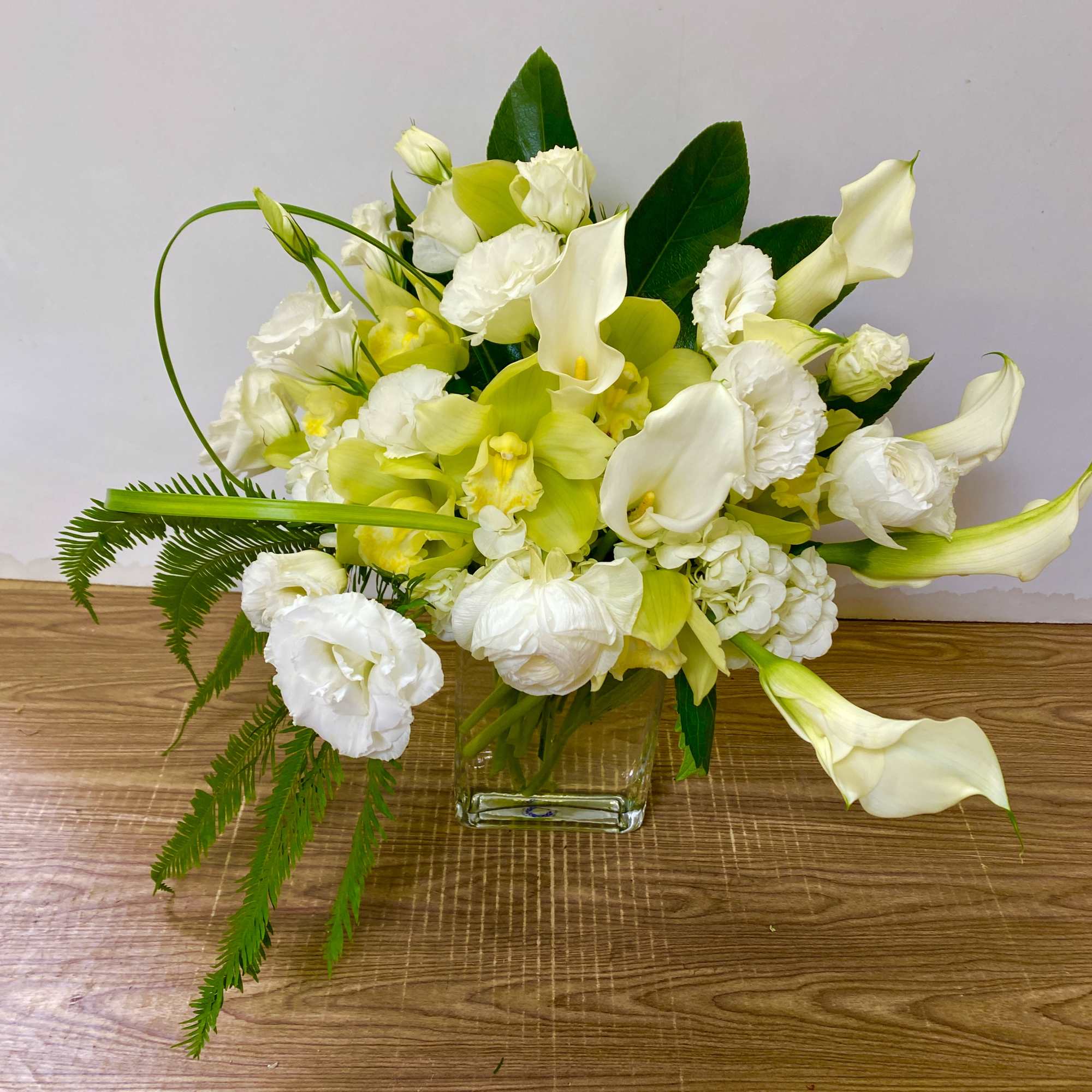 White and yellow floral arrangement in a clear square vase