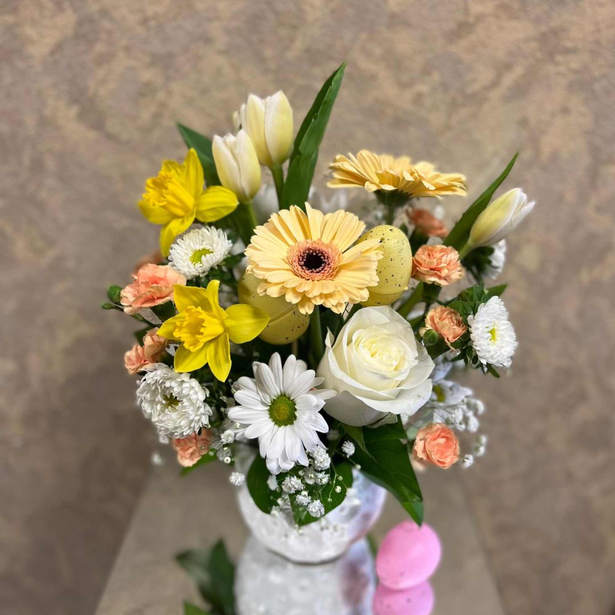 Bouquet of yellow, white, and peach flowers in a white vase