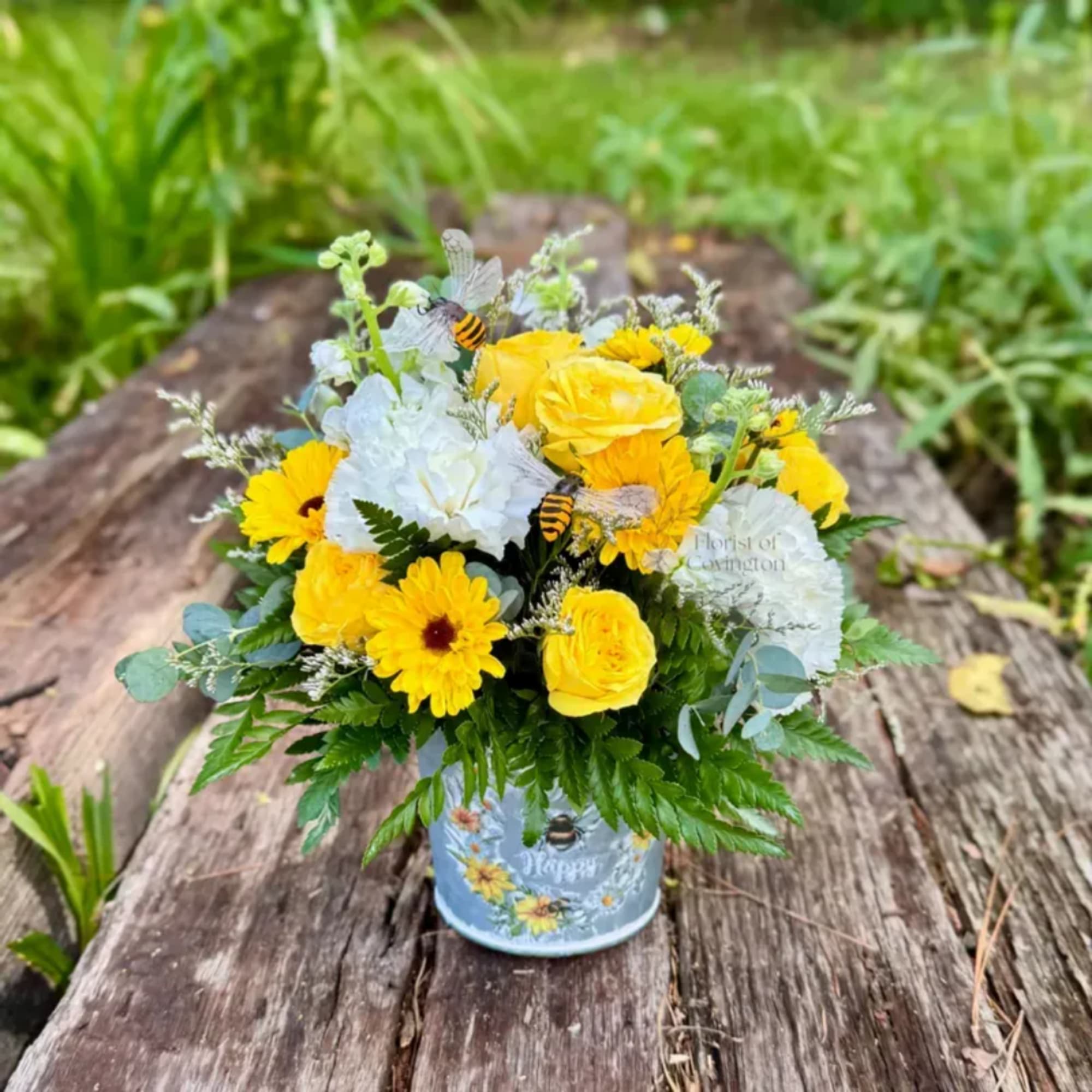 Yellow and white mixed flower arrangement in a blue tin container