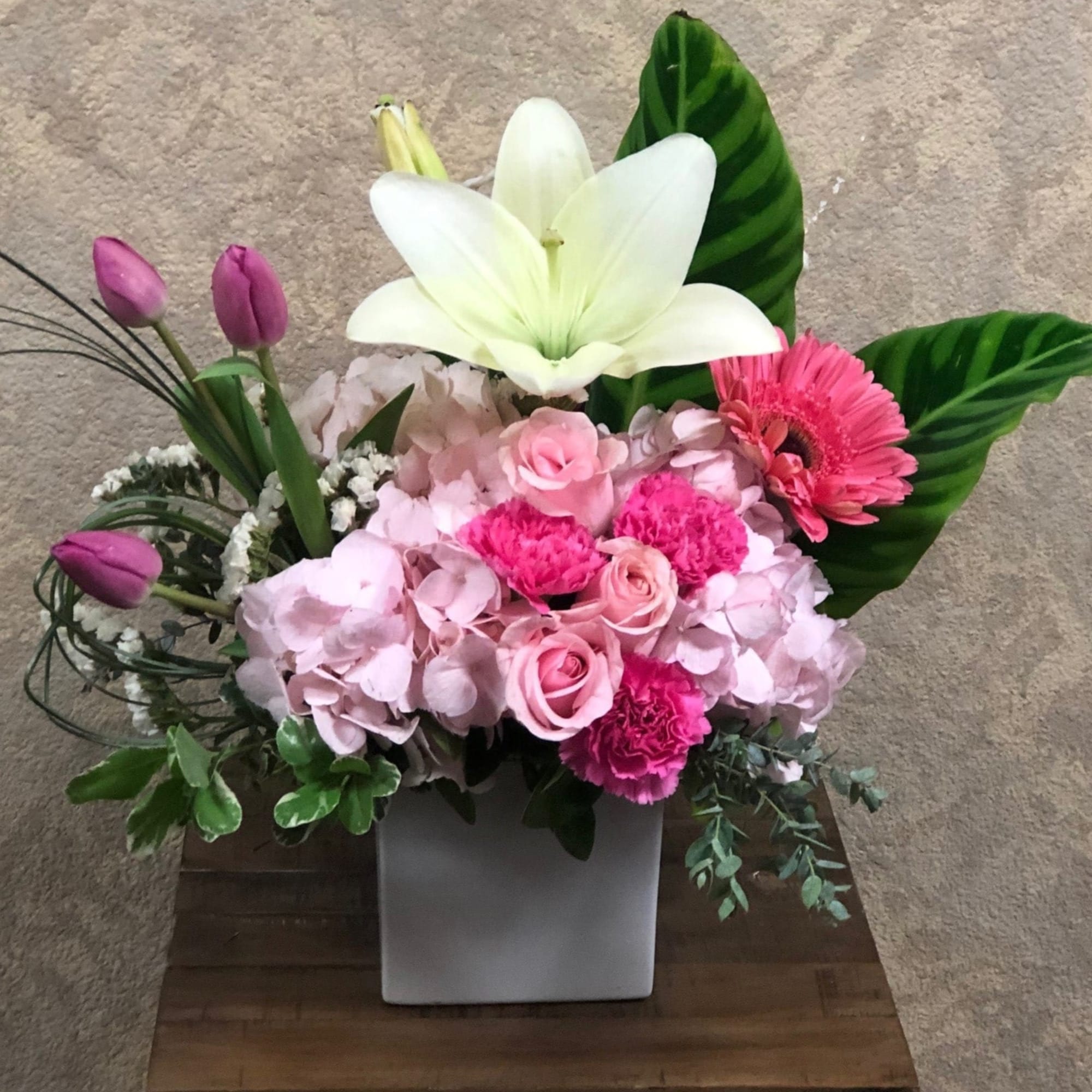 Pink floral arrangement with a white lily in a square vase, photo 2 of 2