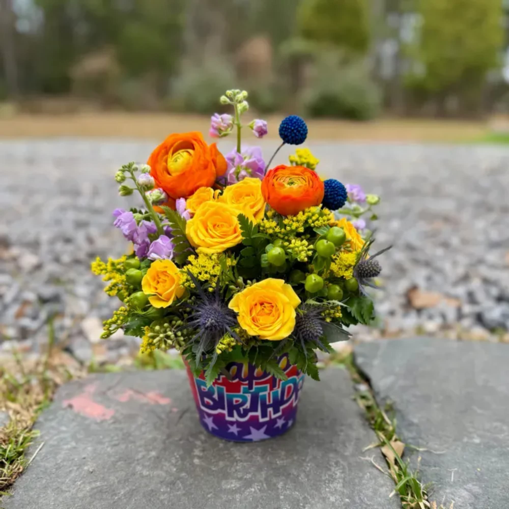 Bright mixed bouquet in a birthday container outdoors