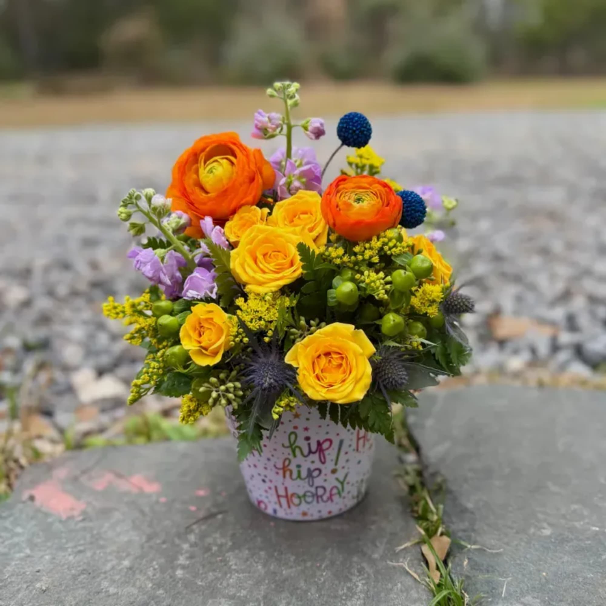 Bright mixed bouquet of orange and yellow roses in a decorated pot