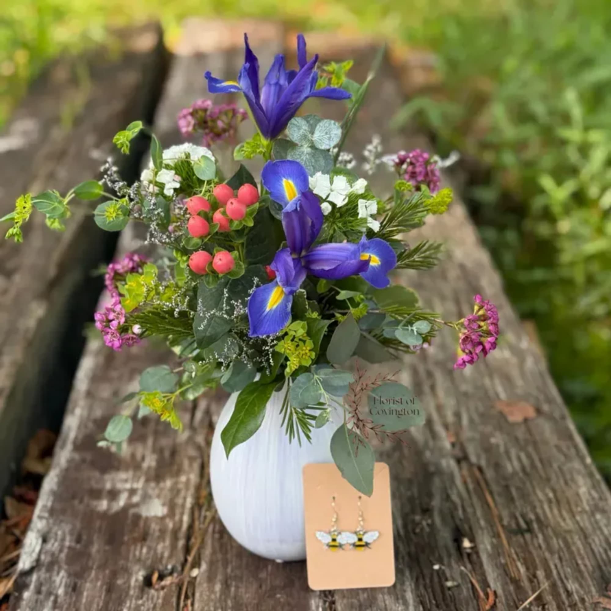 Mixed bouquet in a white vase with blue iris and pink berries