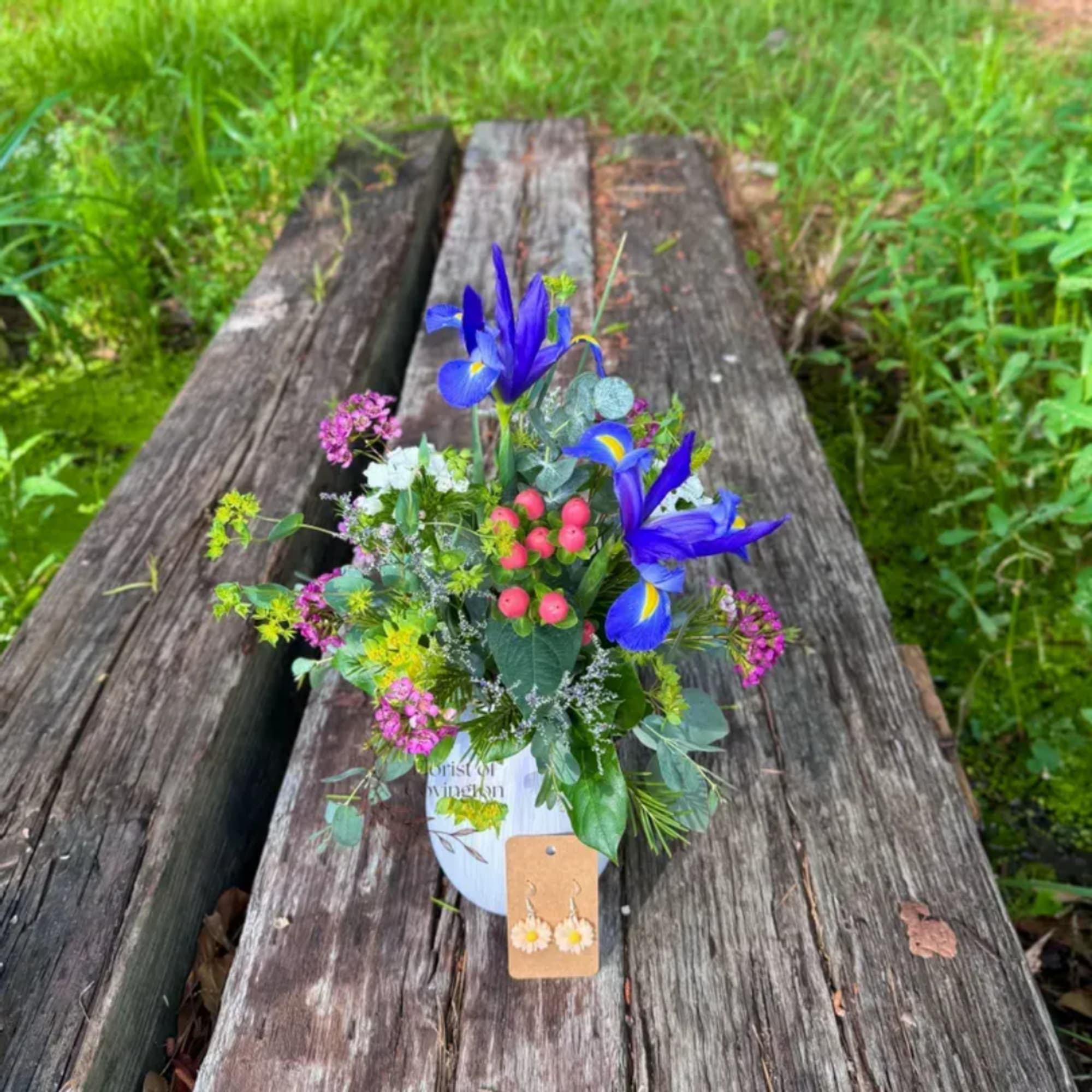 Small mixed bouquet with blue irises and pink berries in a white container