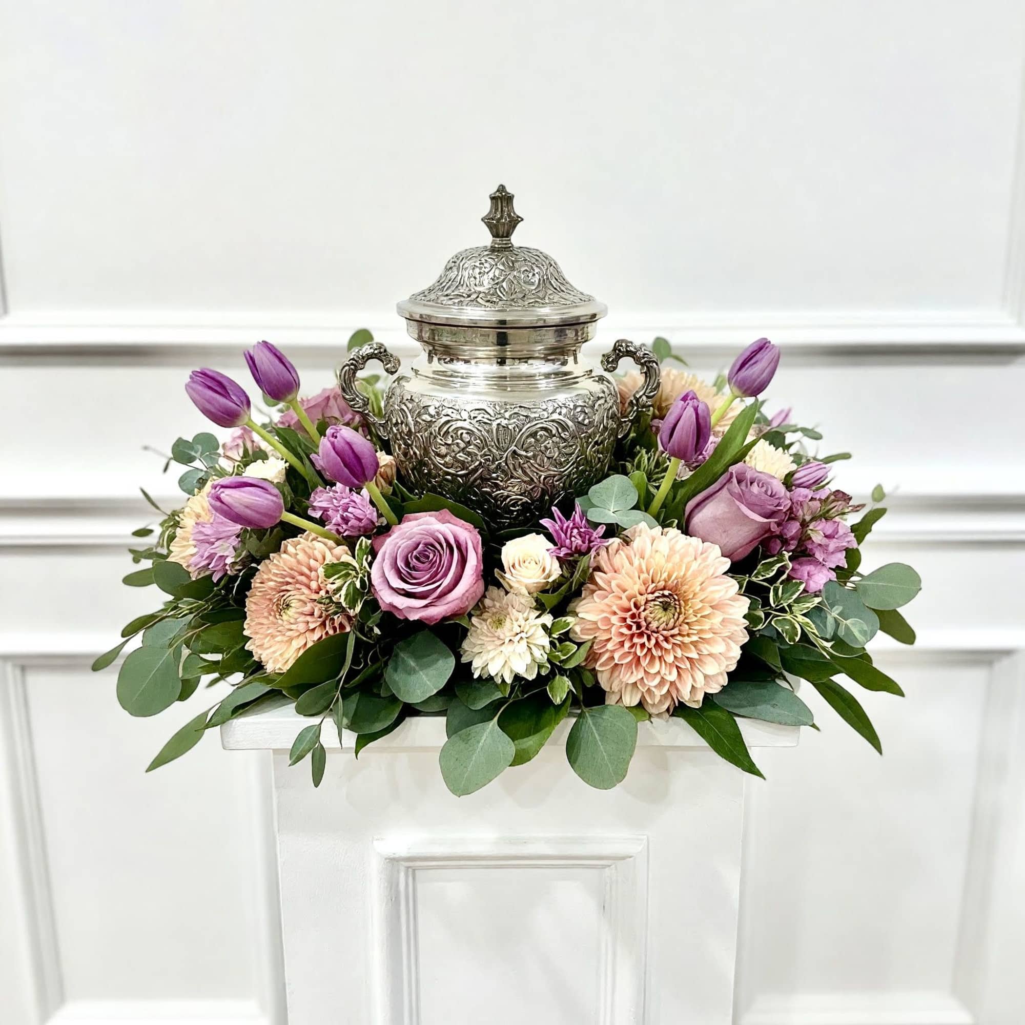 A soft and graceful urn arrangement featuring lavender roses, purple tulips, blush