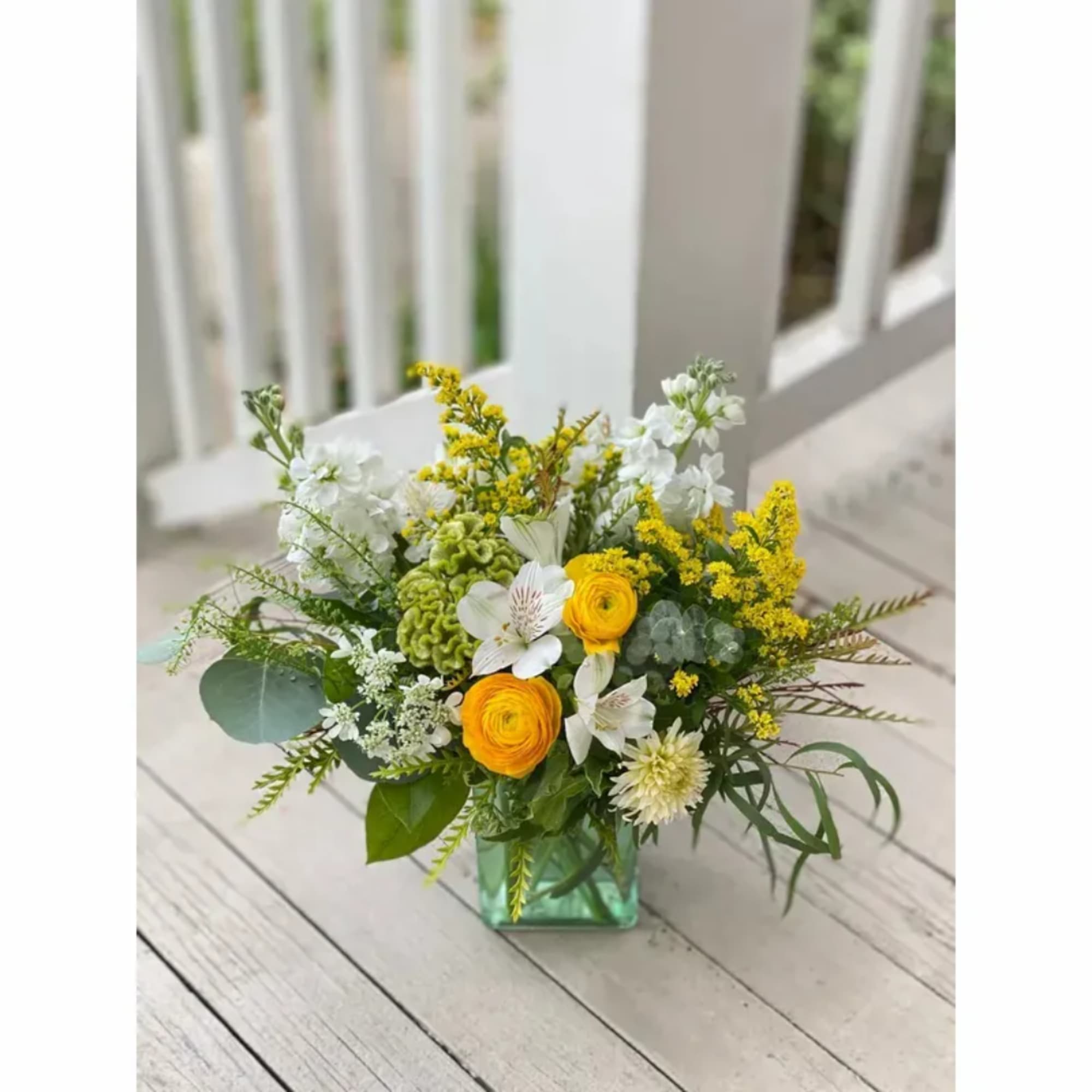 Yellow and white mixed flower arrangement in a square glass vase