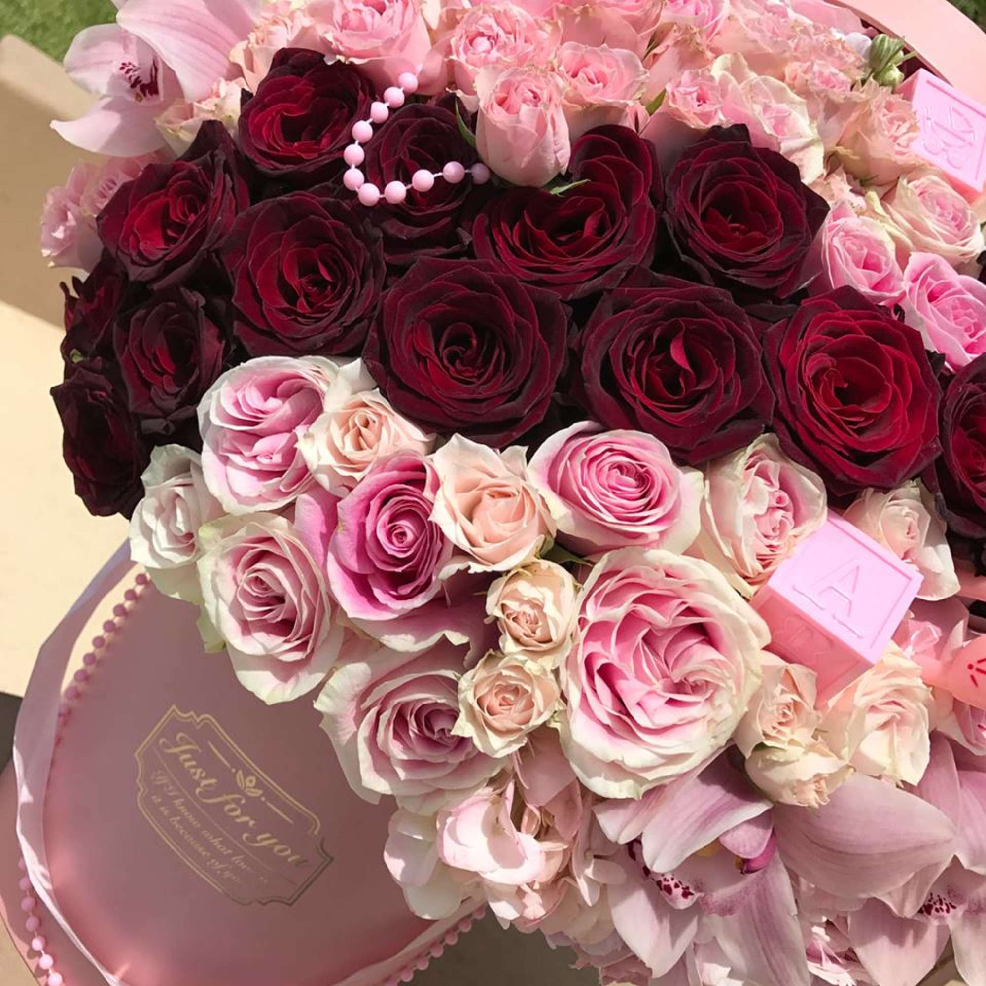 Bouquet of pink and burgundy roses in a round pink box