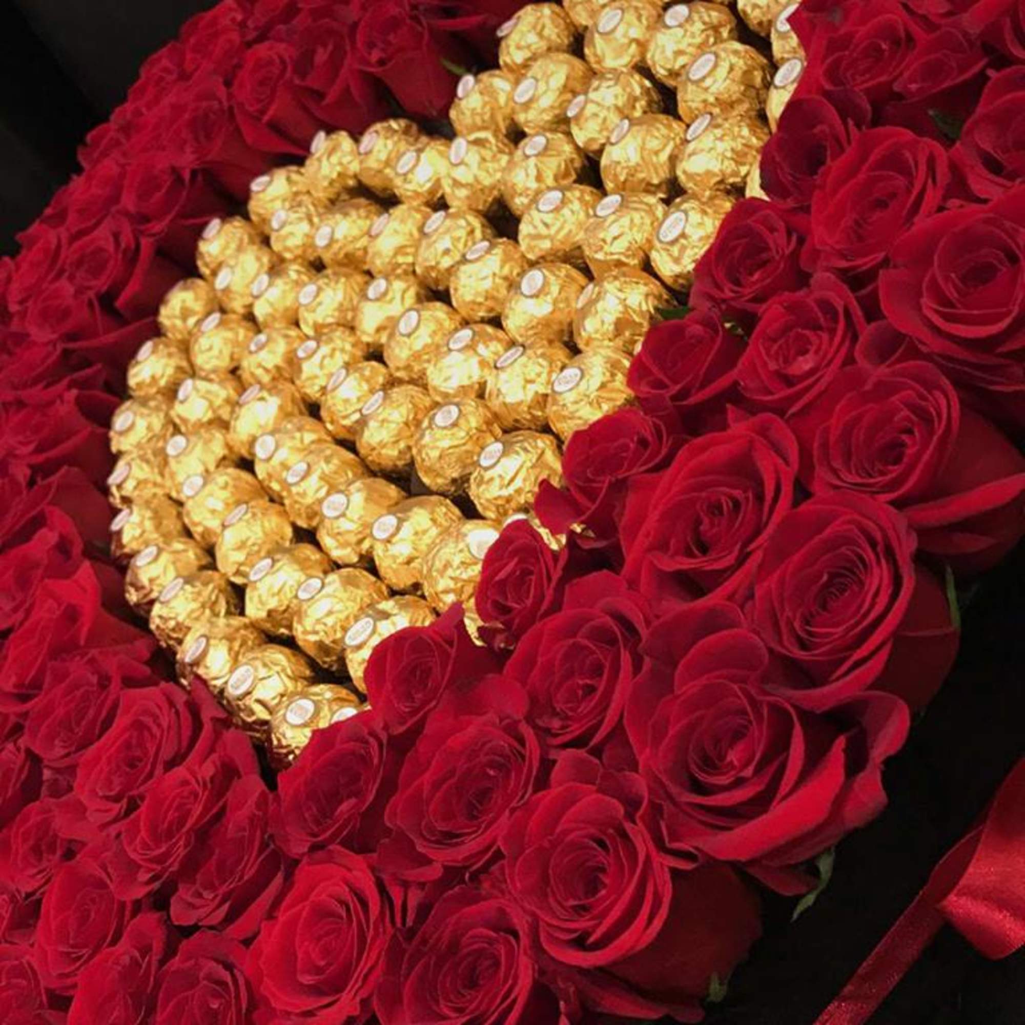 Heart-shaped rose arrangement with gold-wrapped chocolates in the center
