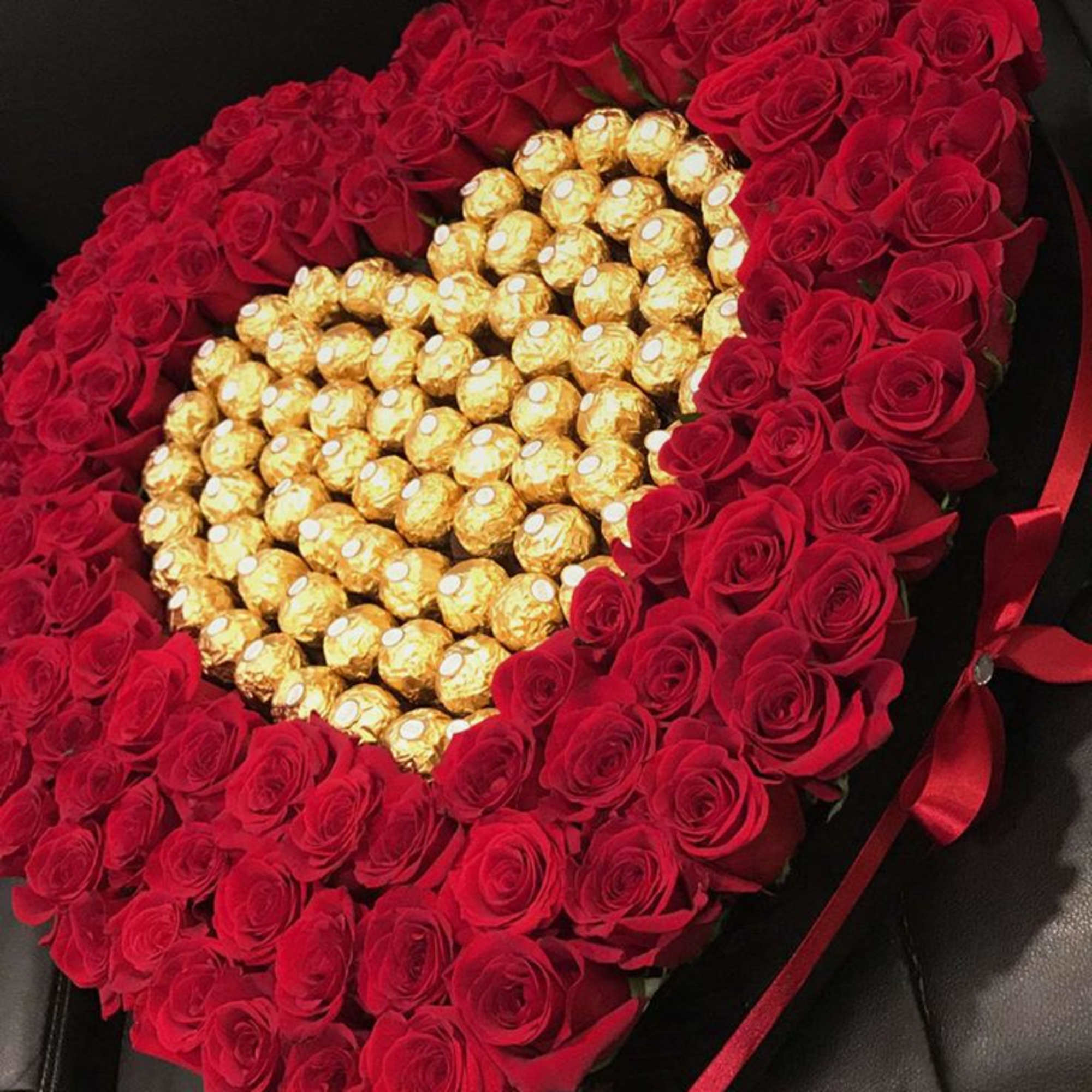 Heart-shaped bouquet of red roses with gold-wrapped chocolates in the center