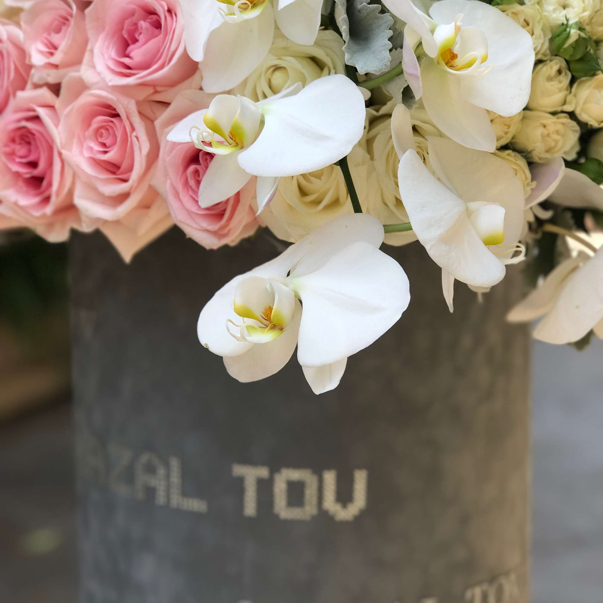 Pink roses and white orchids in a gray hatbox