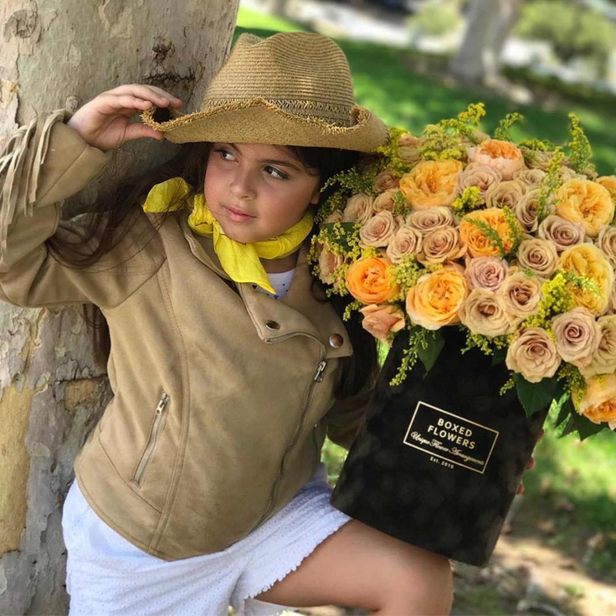 Girl holding a black box of peach and yellow roses