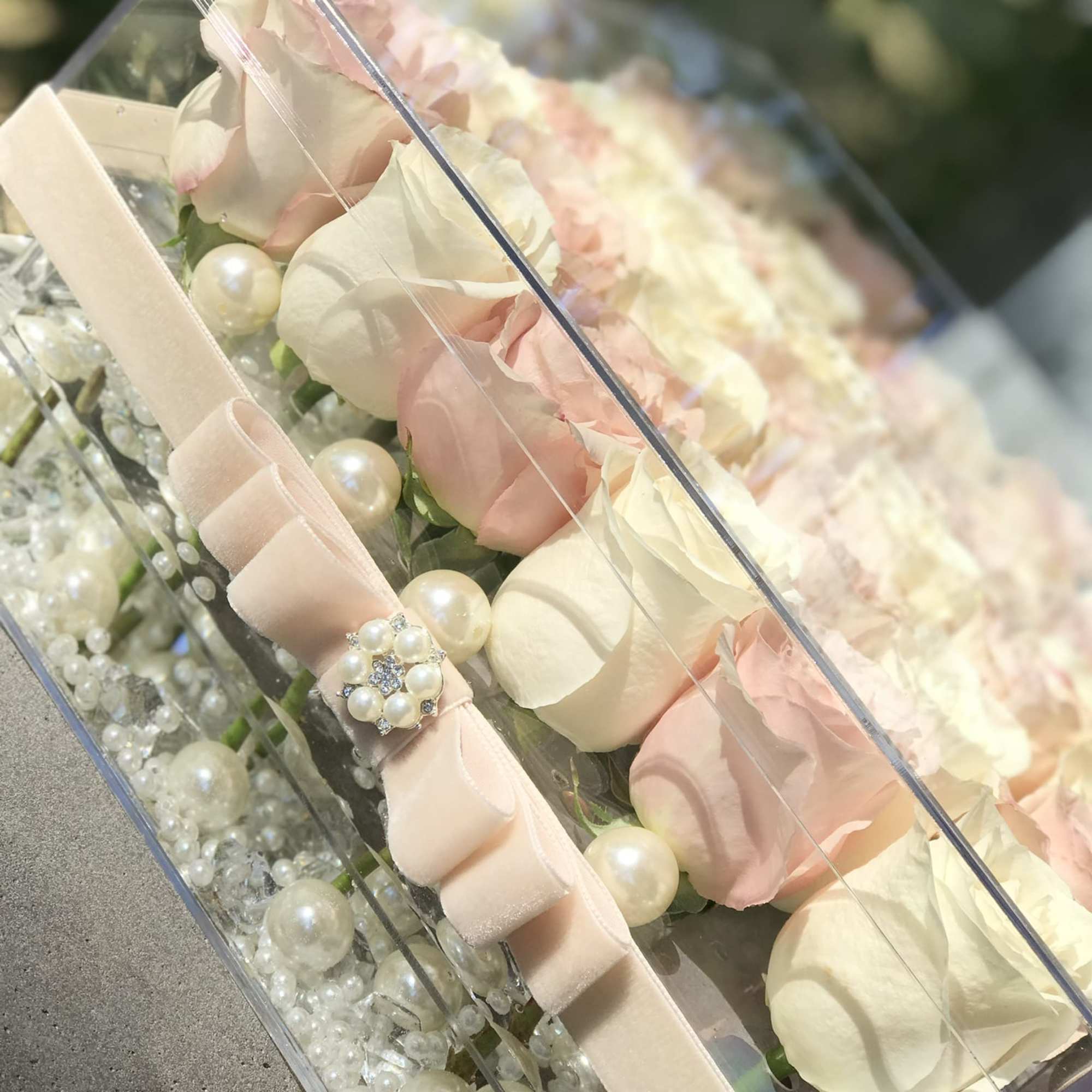 Pastel roses in a clear box with ribbon and pearl accents