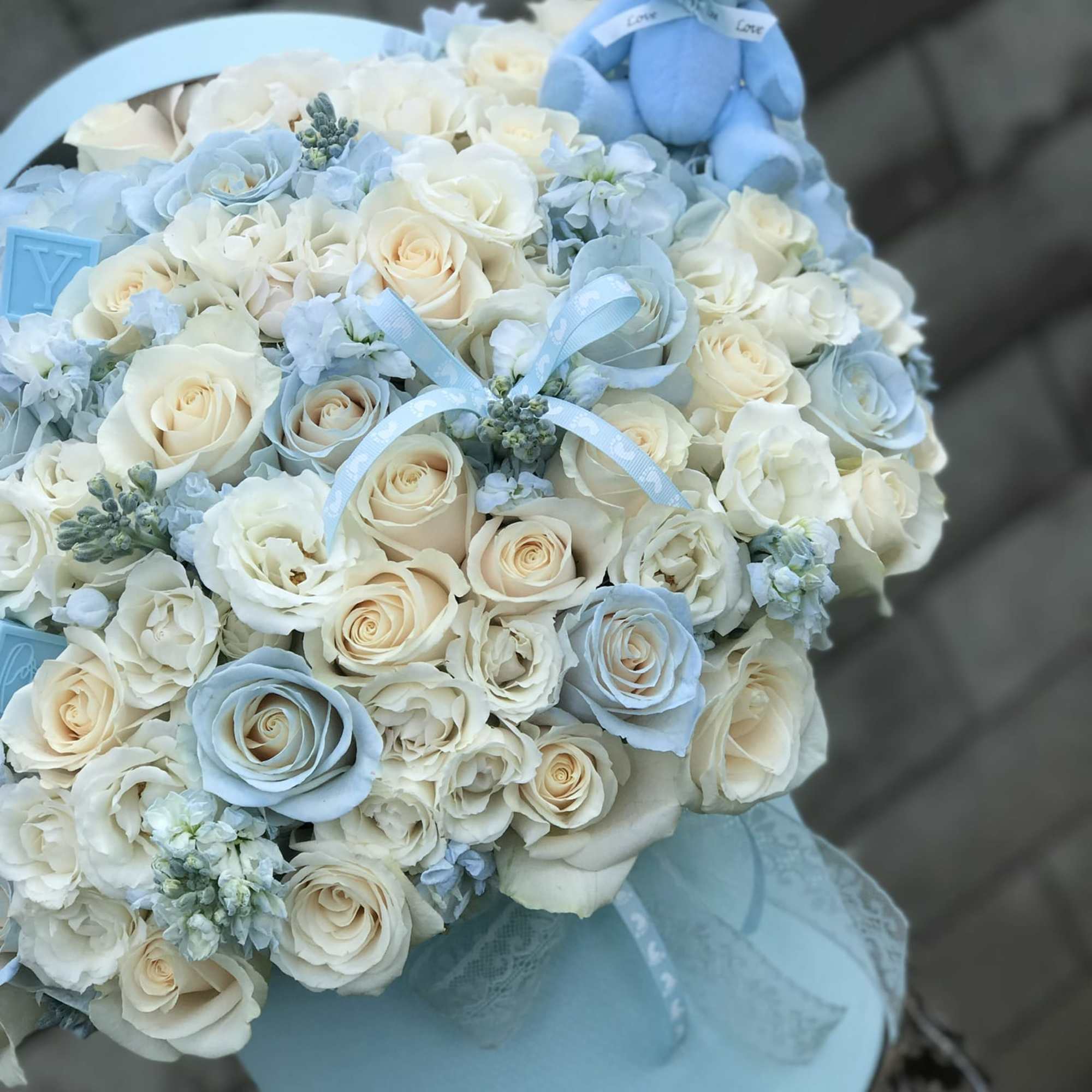 Blue and white rose bouquet with a small teddy bear