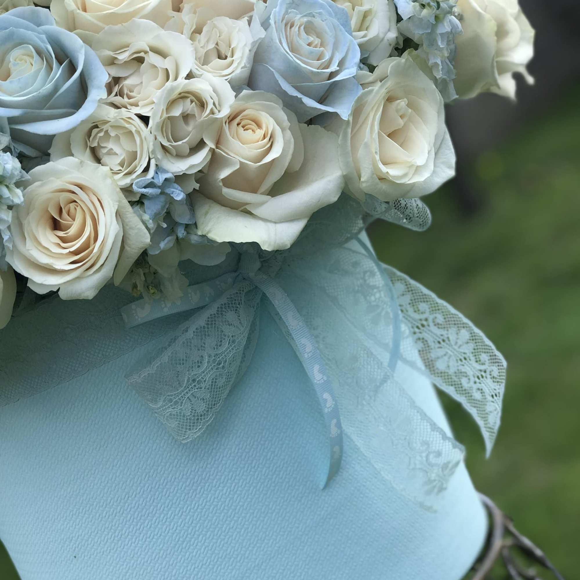 Bouquet of white and pale blue roses wrapped in light blue lace