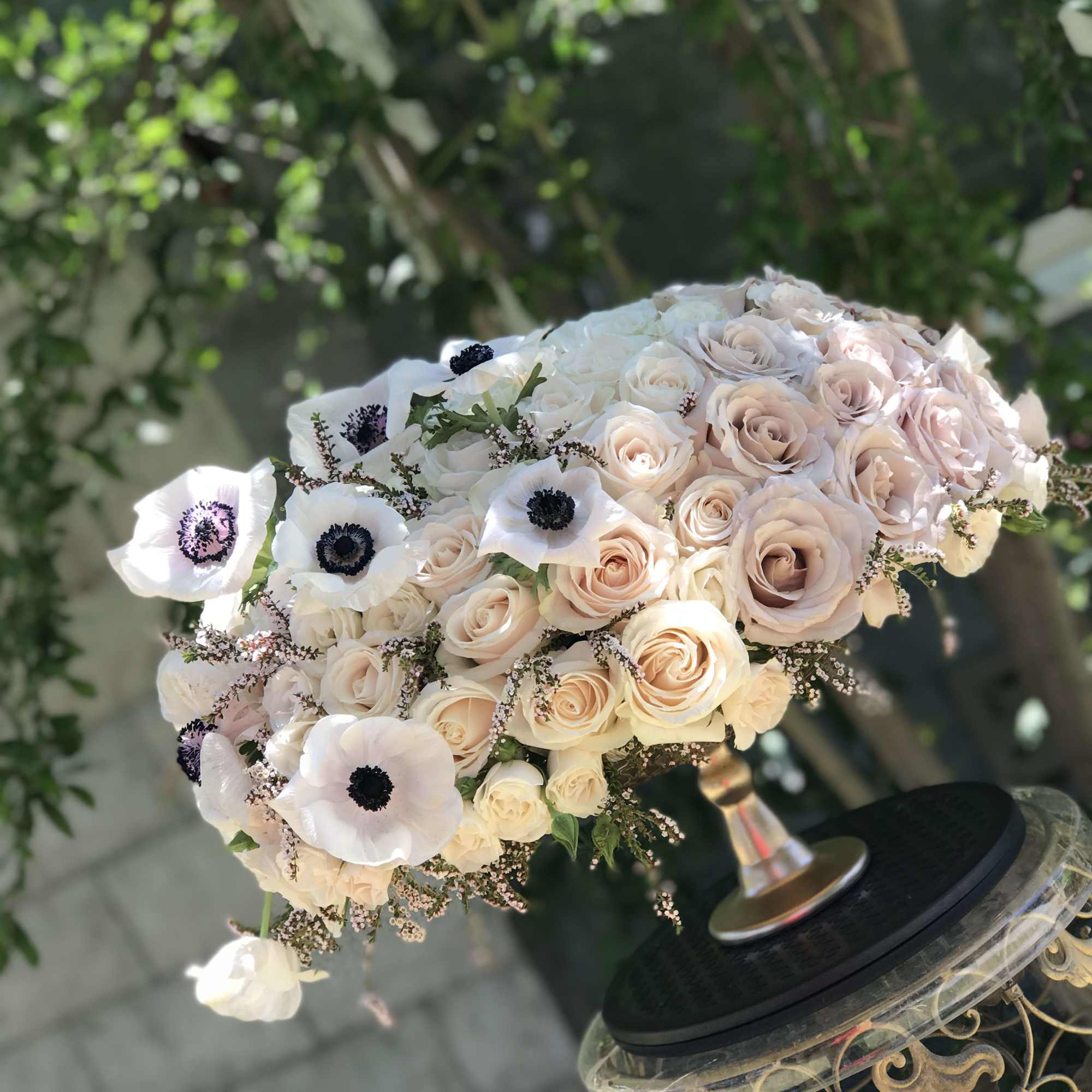 Bouquet of pale roses and white anemones in a decorative stand