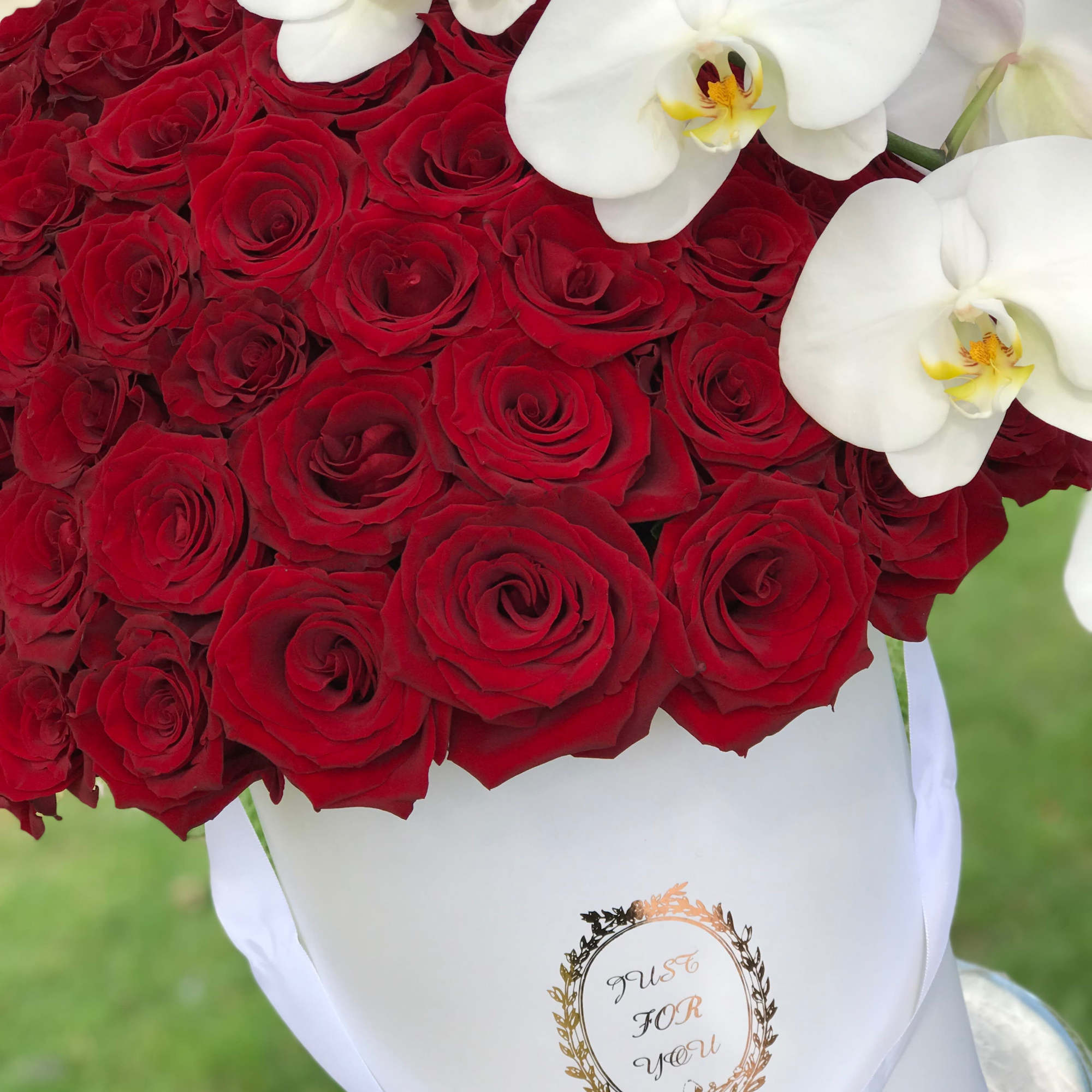 Bouquet of red roses with white orchids in a white hatbox
