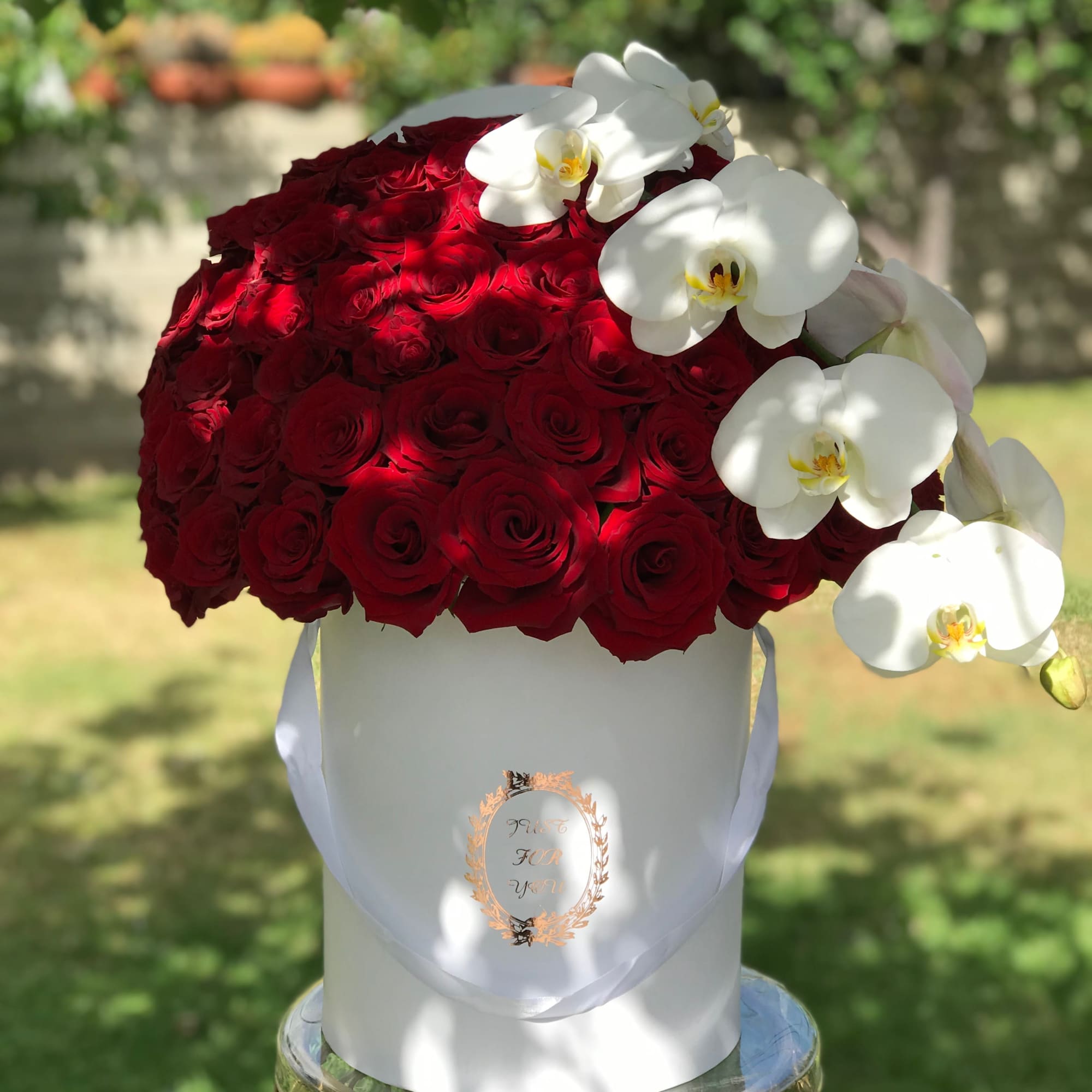 Red rose arrangement with white orchids in a white hatbox