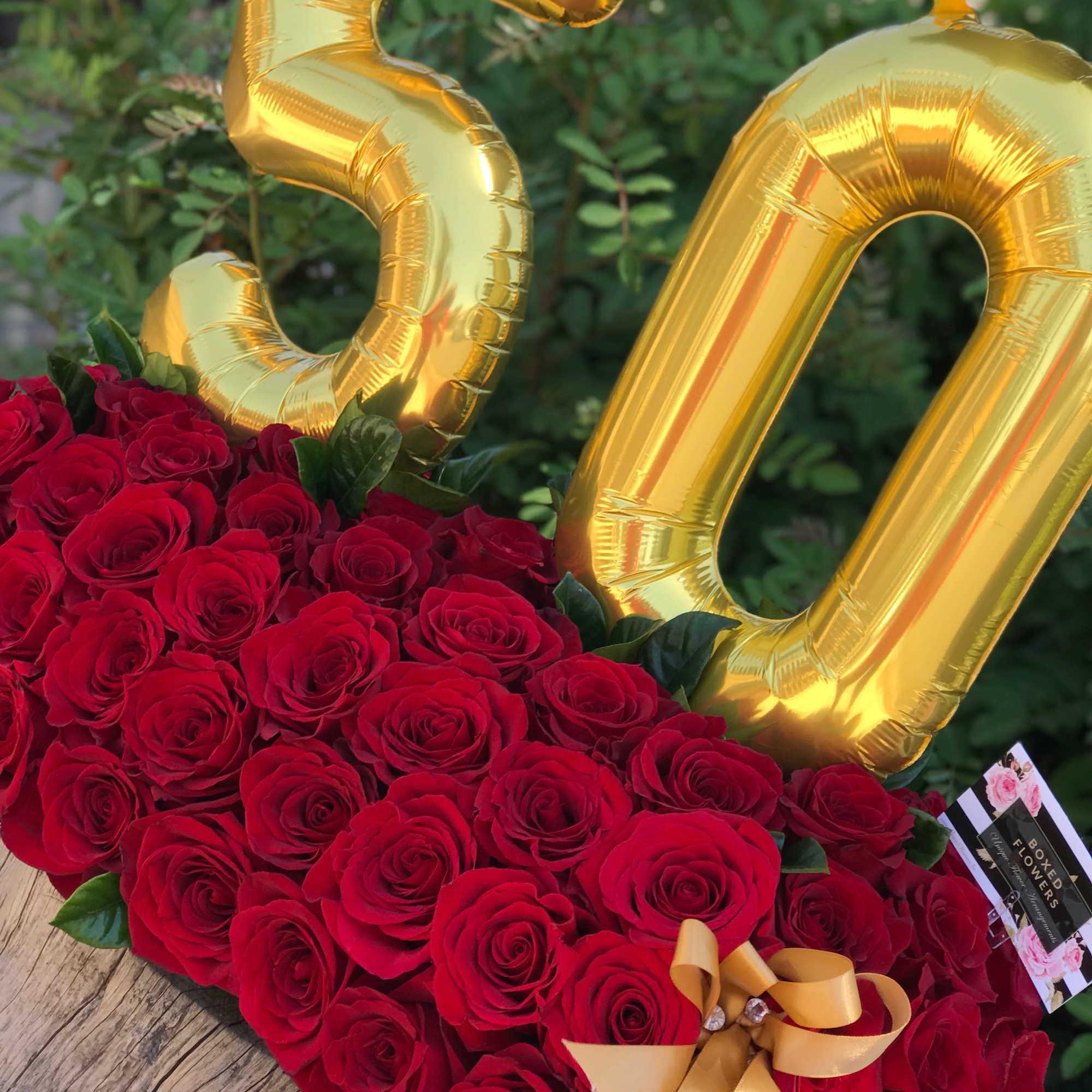 Heart-shaped red rose arrangement with gold number balloons