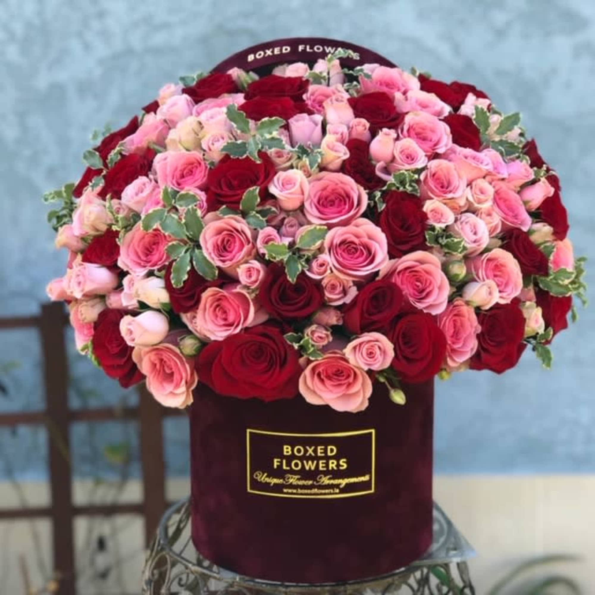 Boxed arrangement of pink and red roses in a burgundy hatbox