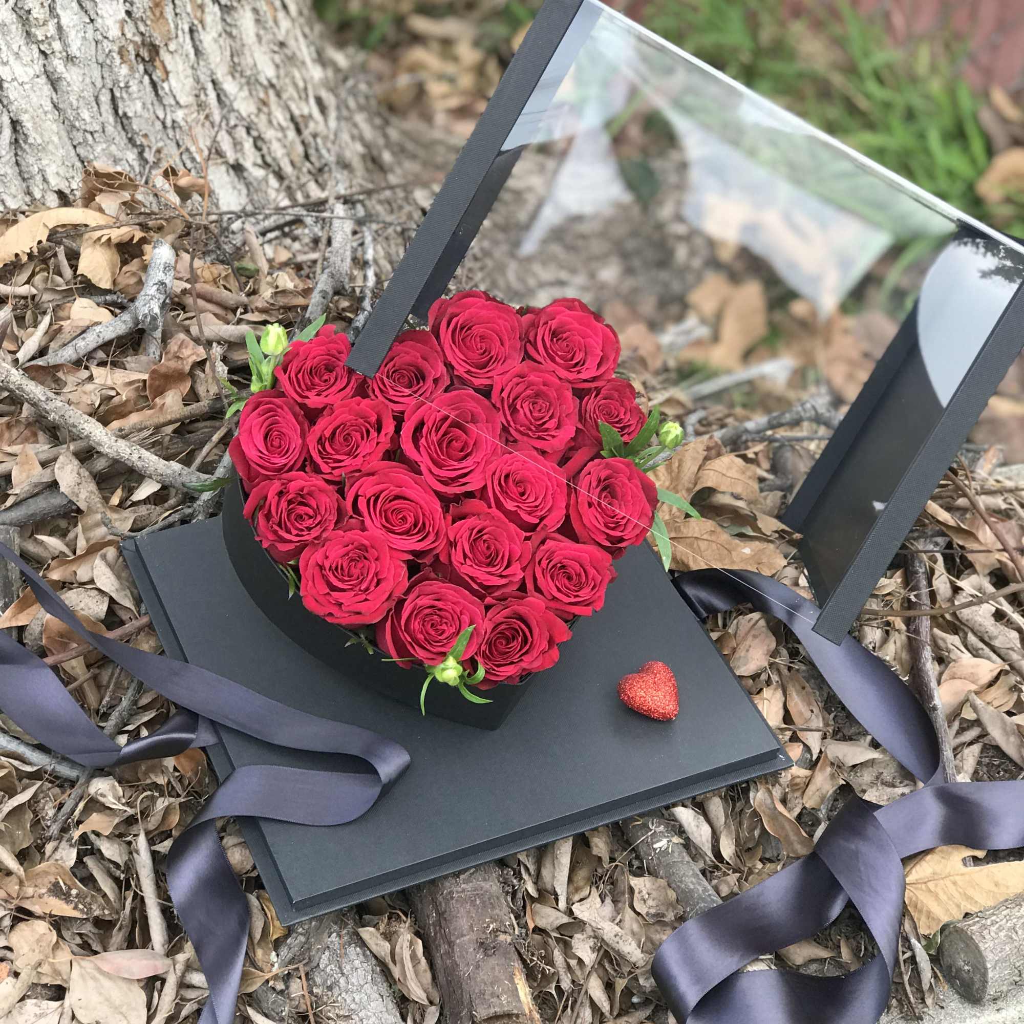 Heart-shaped box of red roses with a ribbon and small heart accent