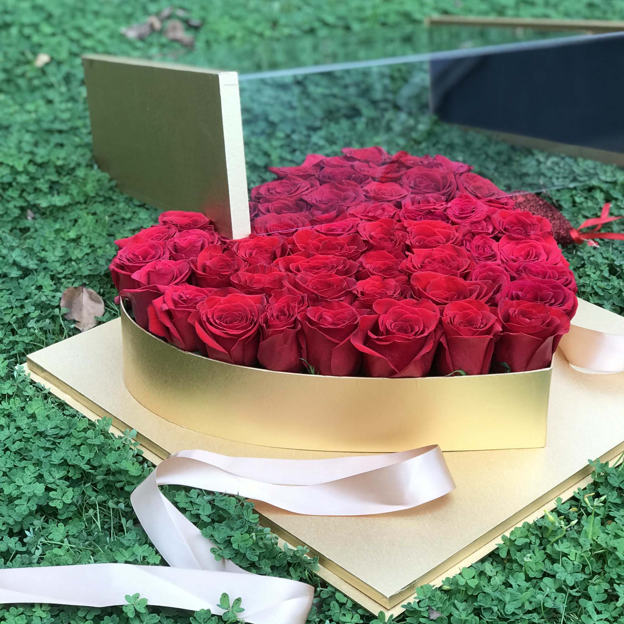 Heart-shaped box filled with red roses and a ribbon