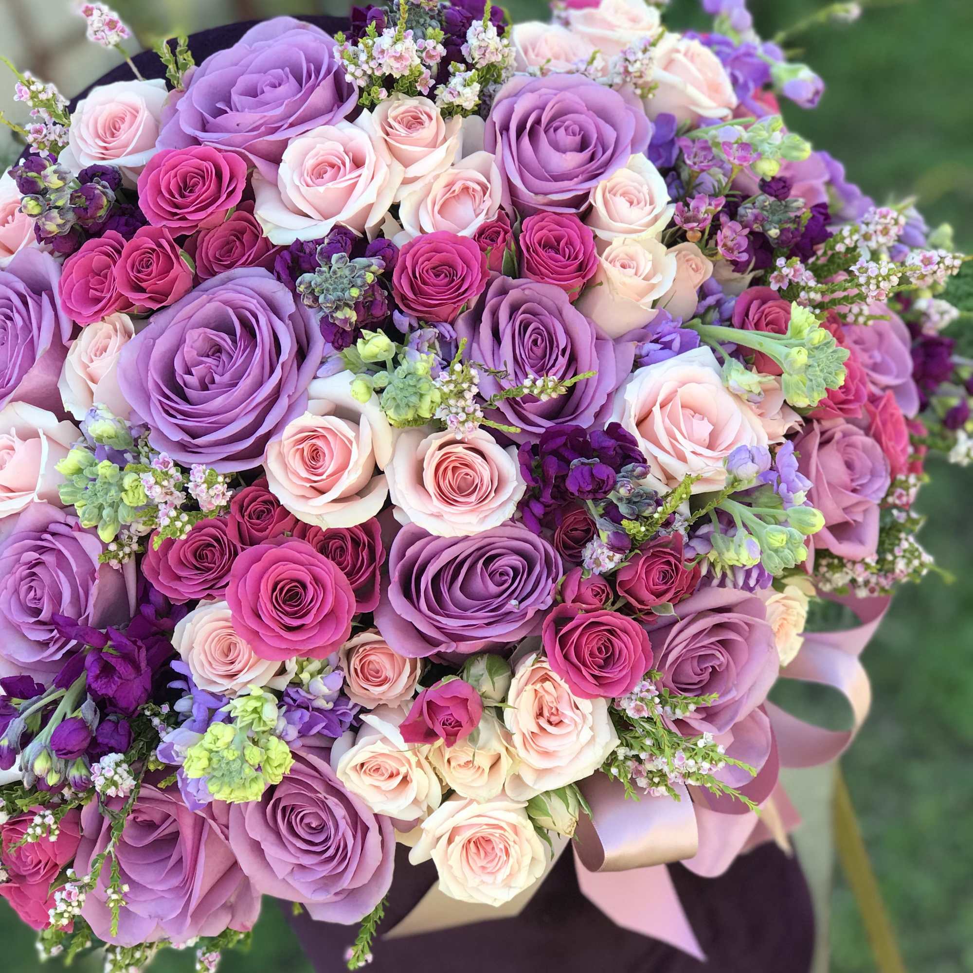 Large bouquet of pink and purple roses with small filler flowers