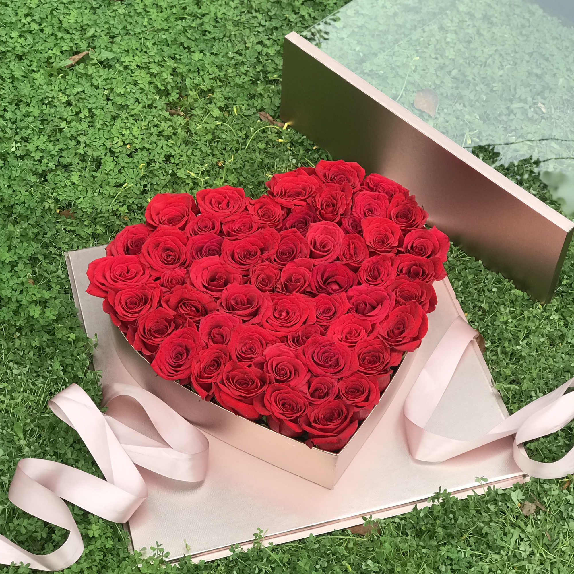 Heart-shaped box of red roses with a pink ribbon