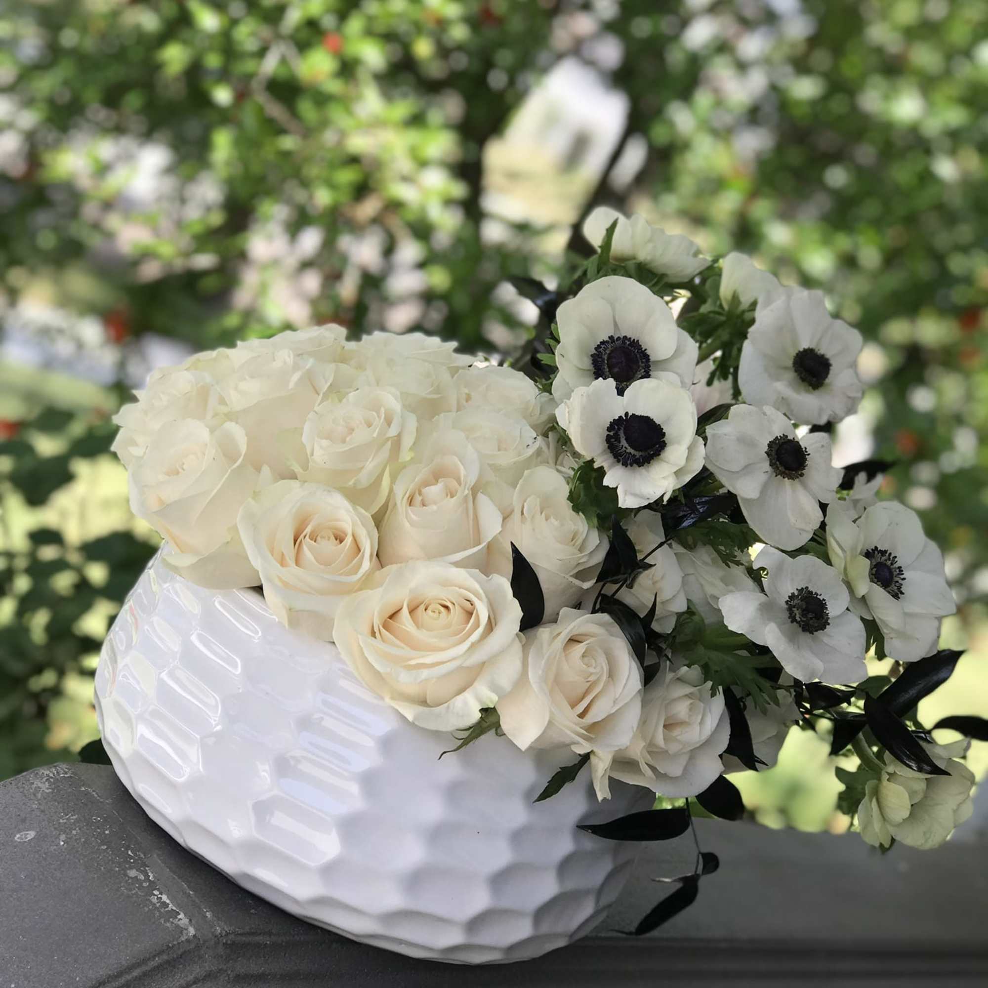 White roses and anemones arranged in a white vase