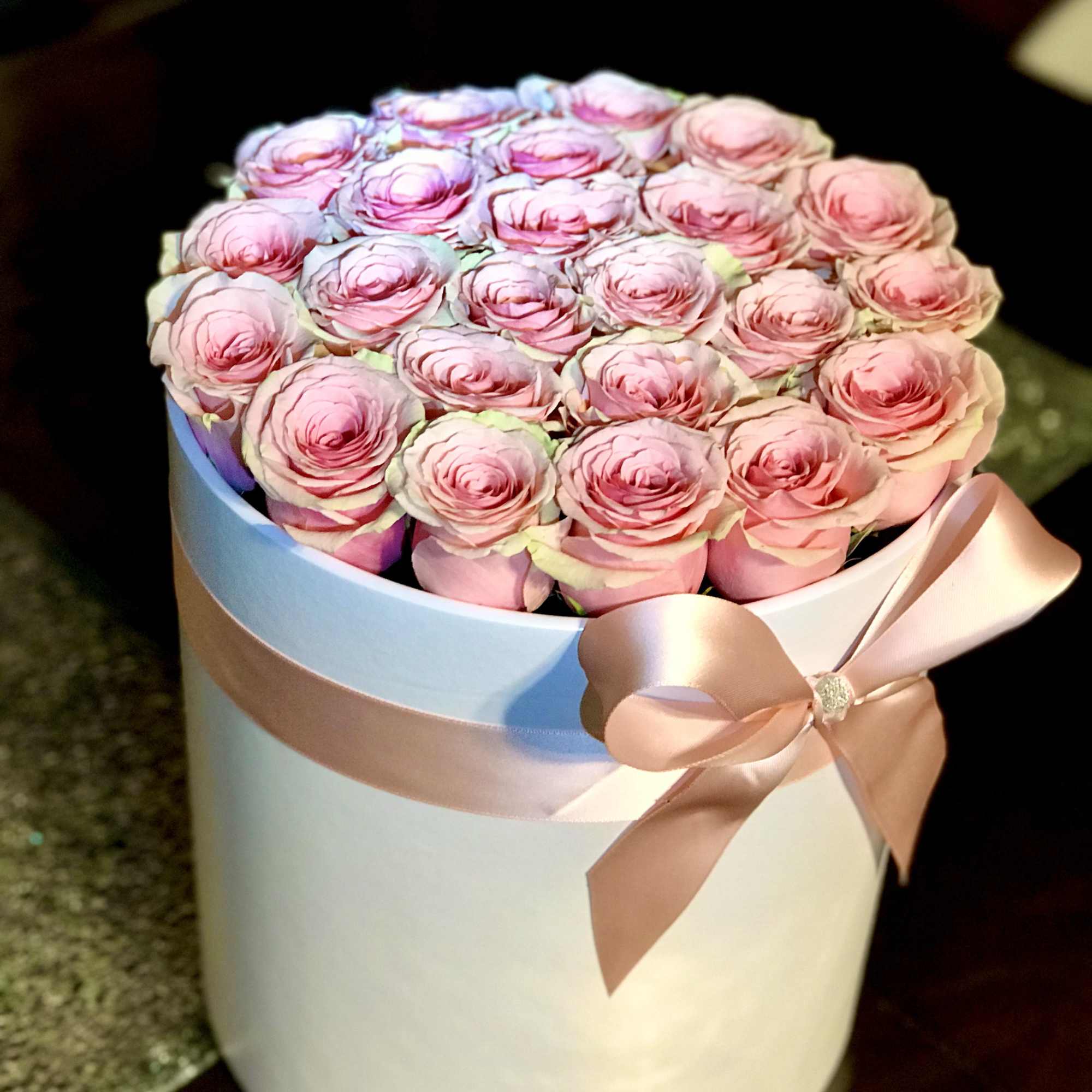 Pink roses arranged in a white hat box with a satin ribbon