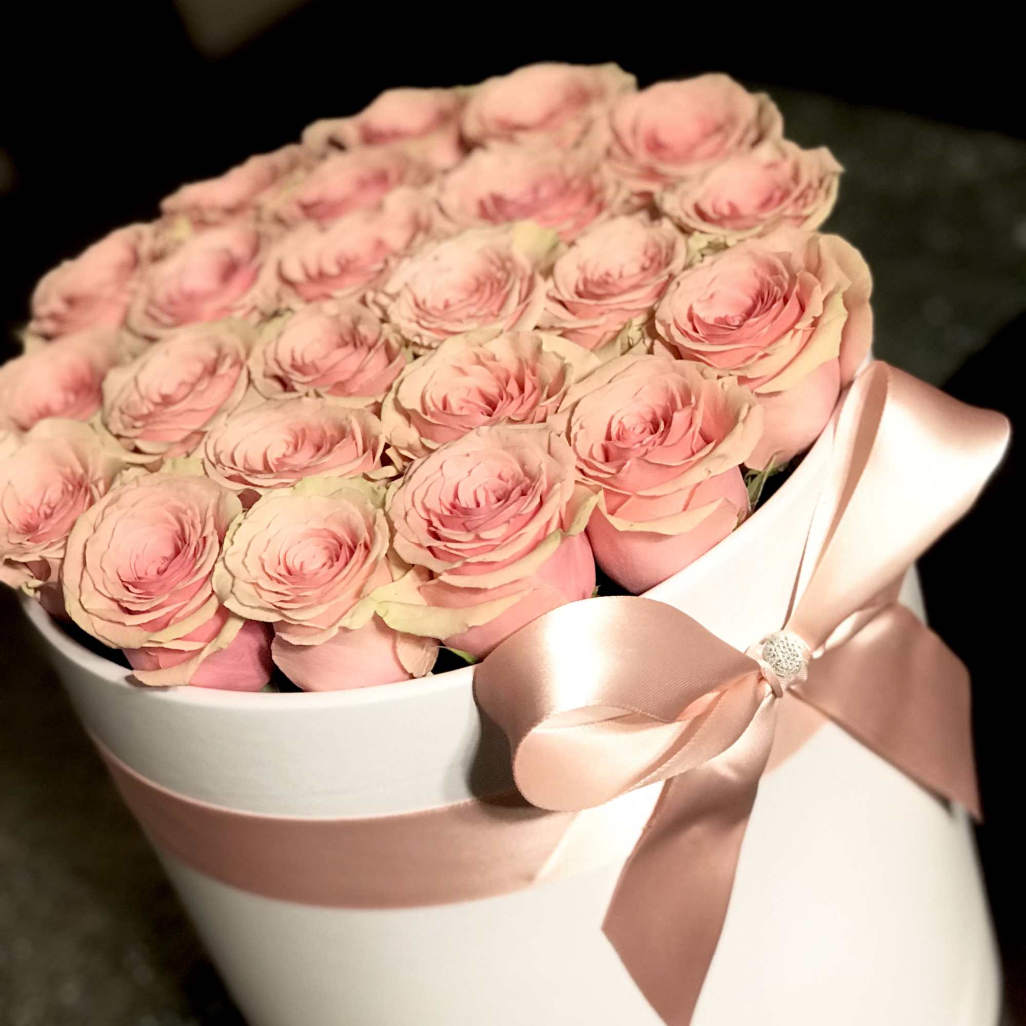 Bouquet of pink roses wrapped in white paper with a pink ribbon
