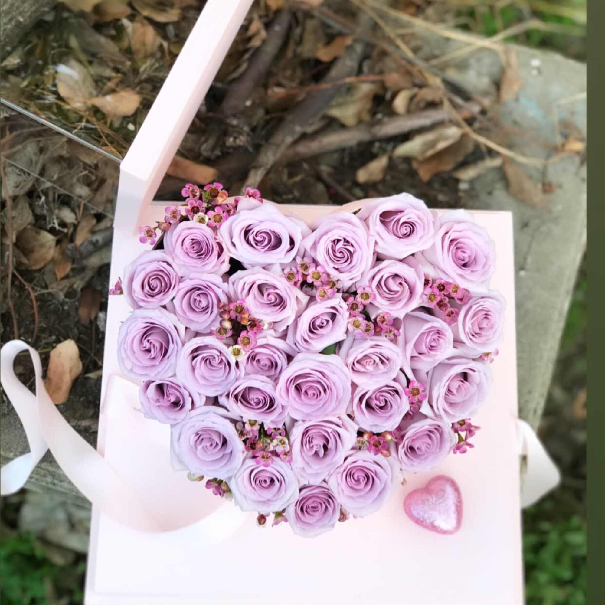 Heart-shaped bouquet of lavender roses in a pink box