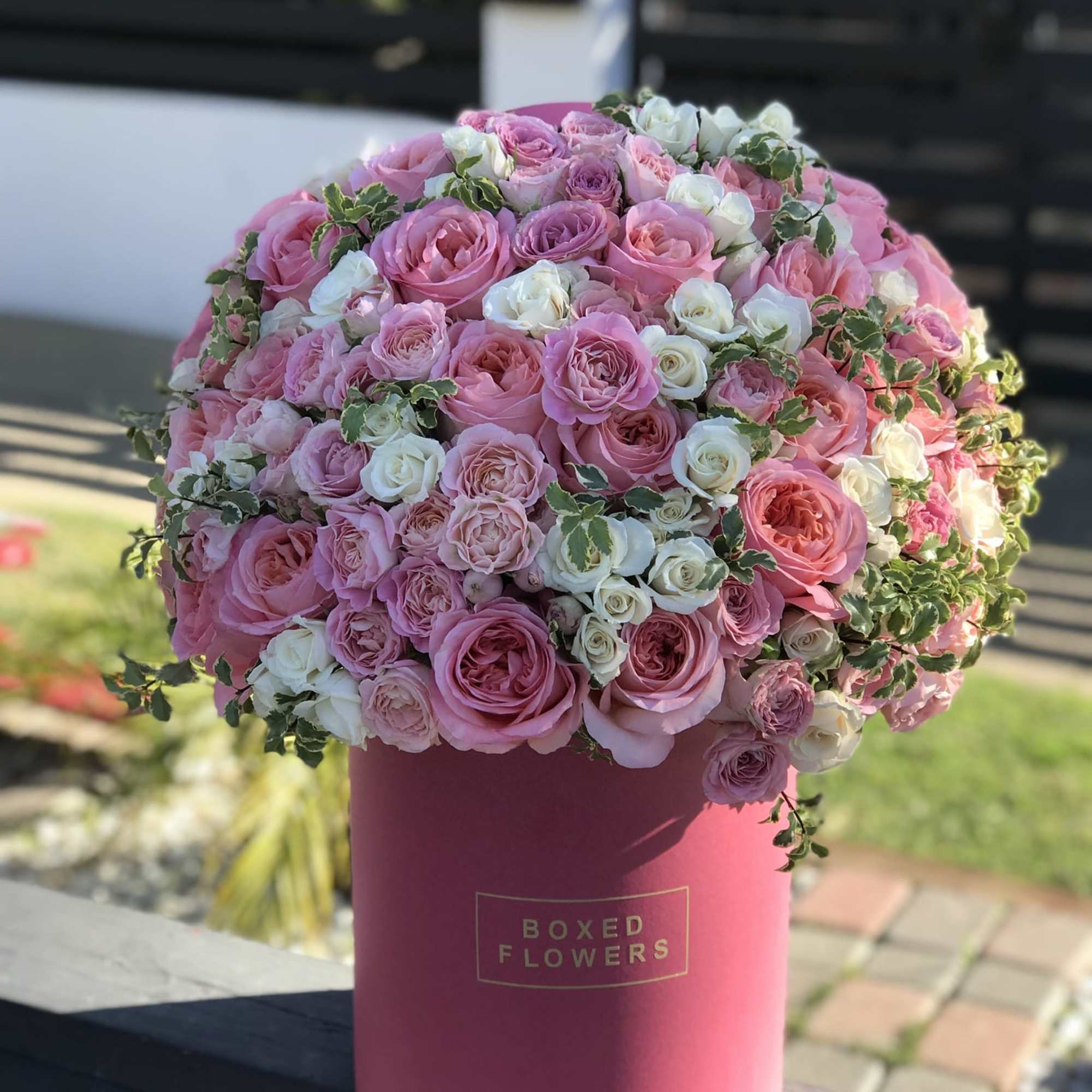 Pink and white roses arranged in a round hatbox