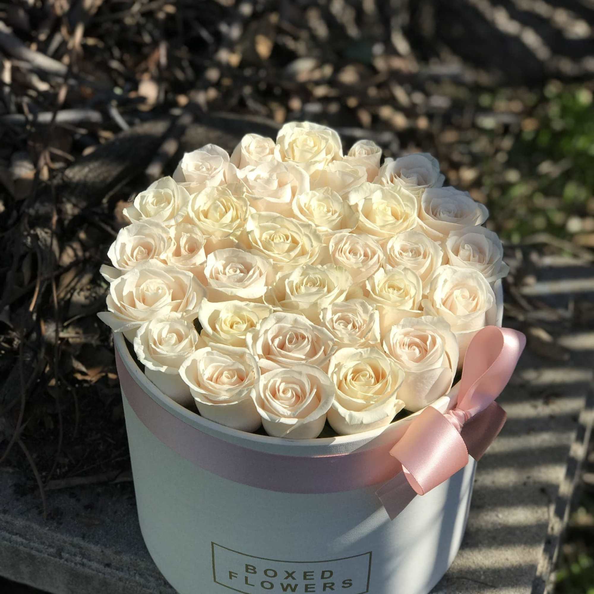 White box filled with ivory/off white roses hugged with a beautiful satin