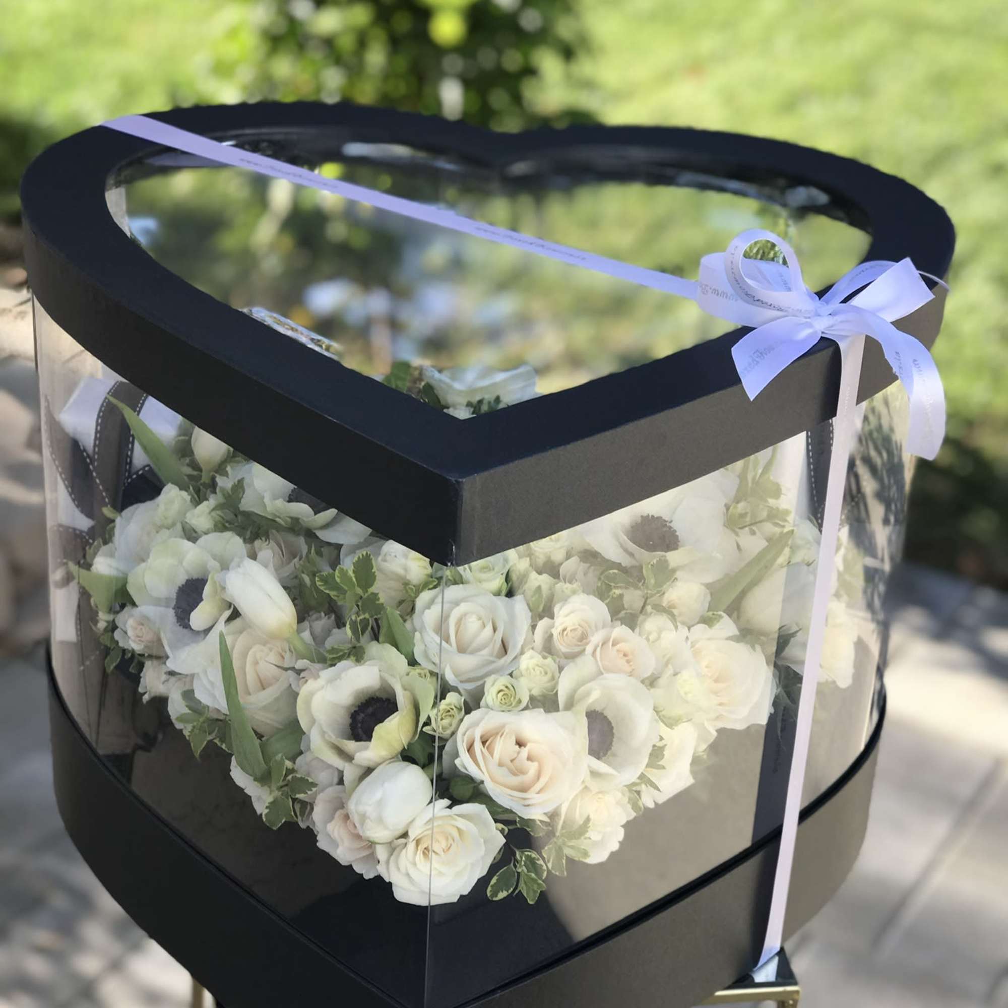 Heart-shaped box of white roses and flowers tied with a ribbon