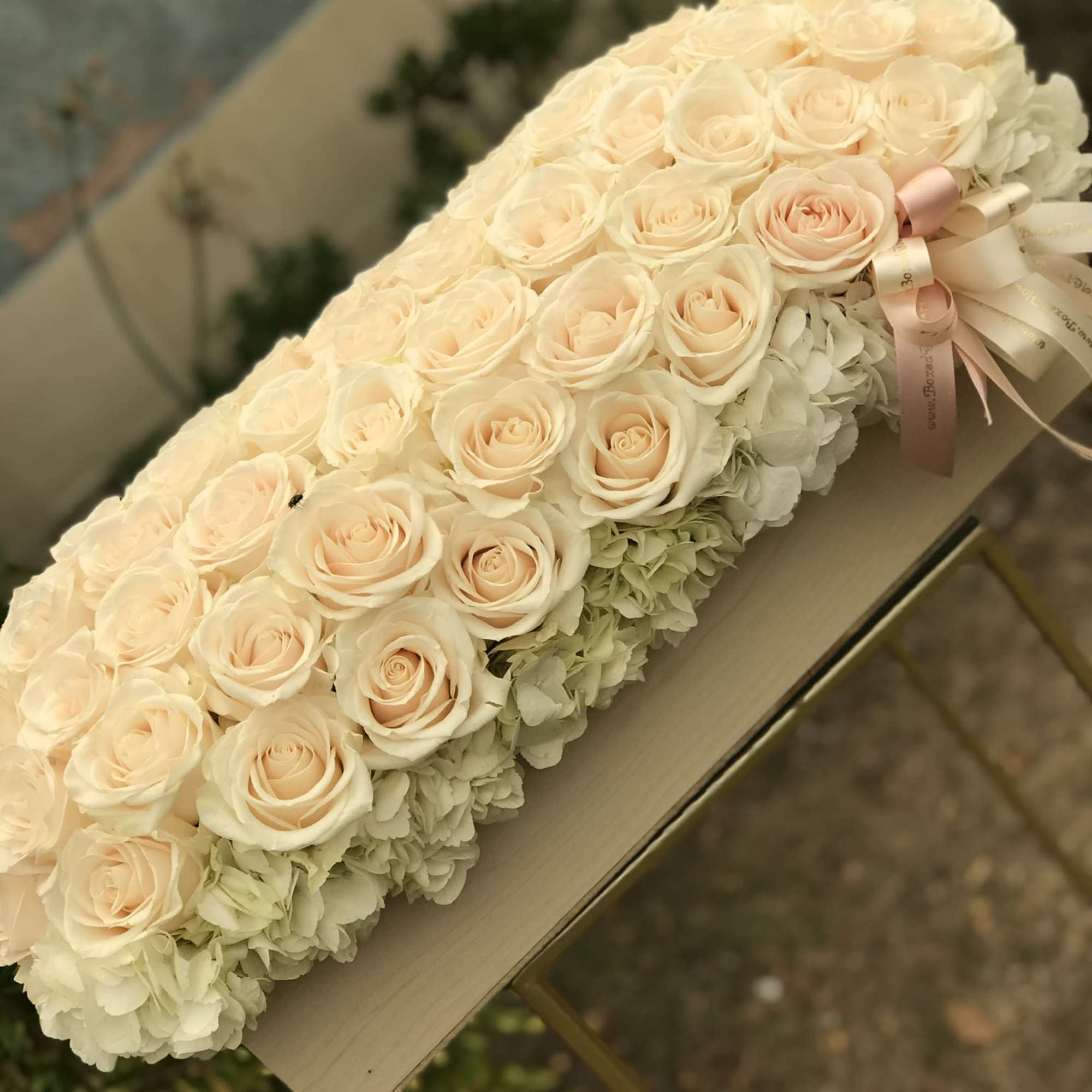 Cream rose bouquet with pale hydrangeas and a pink ribbon