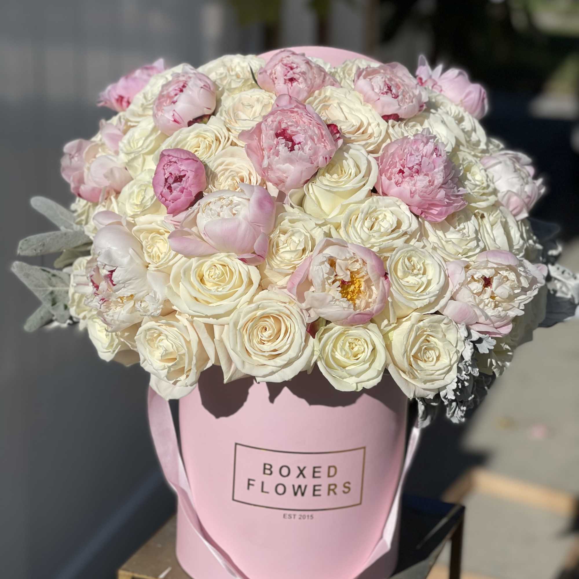 Pink and cream roses and peonies in a pink hat box
