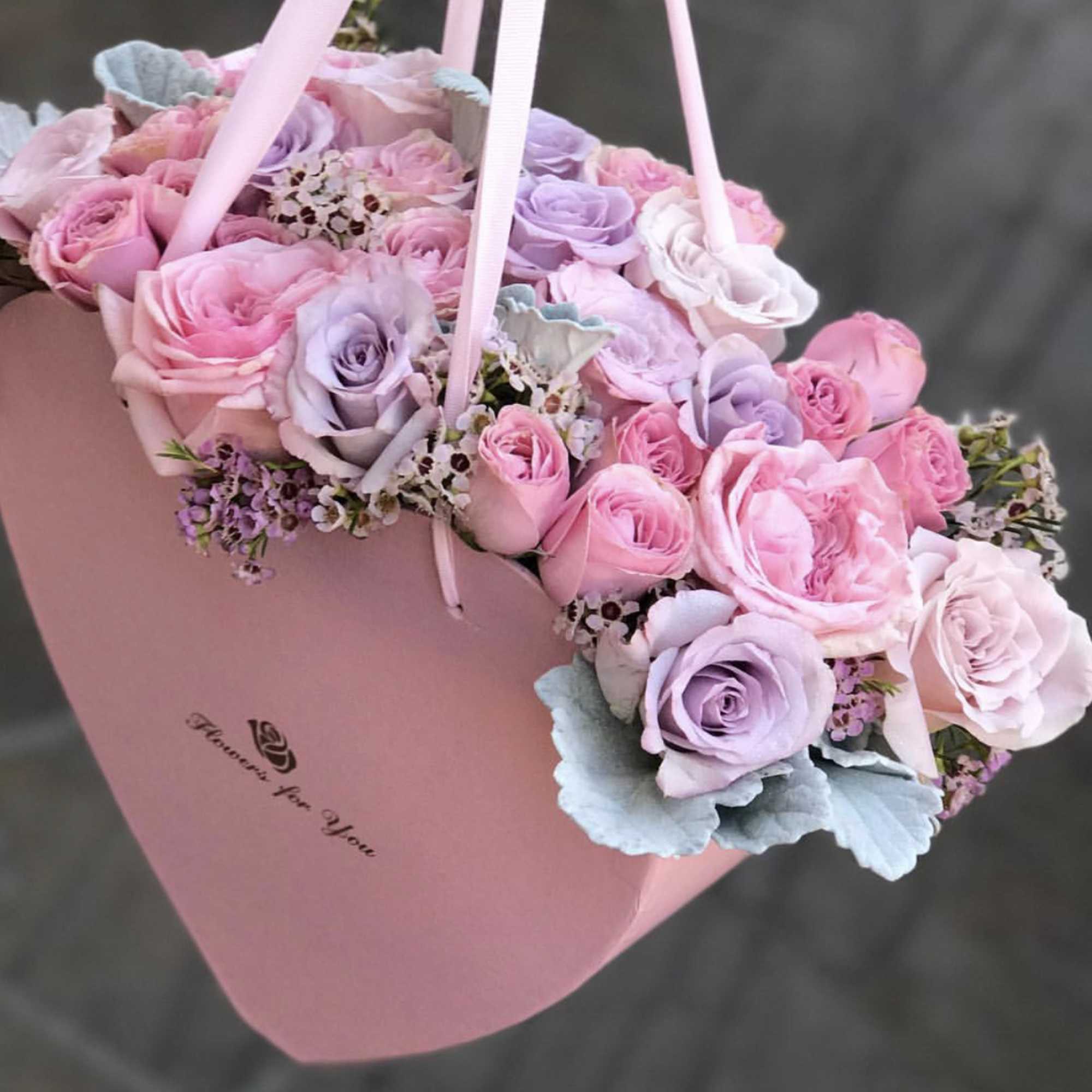 Pink and lavender roses arranged in a pink heart-shaped box