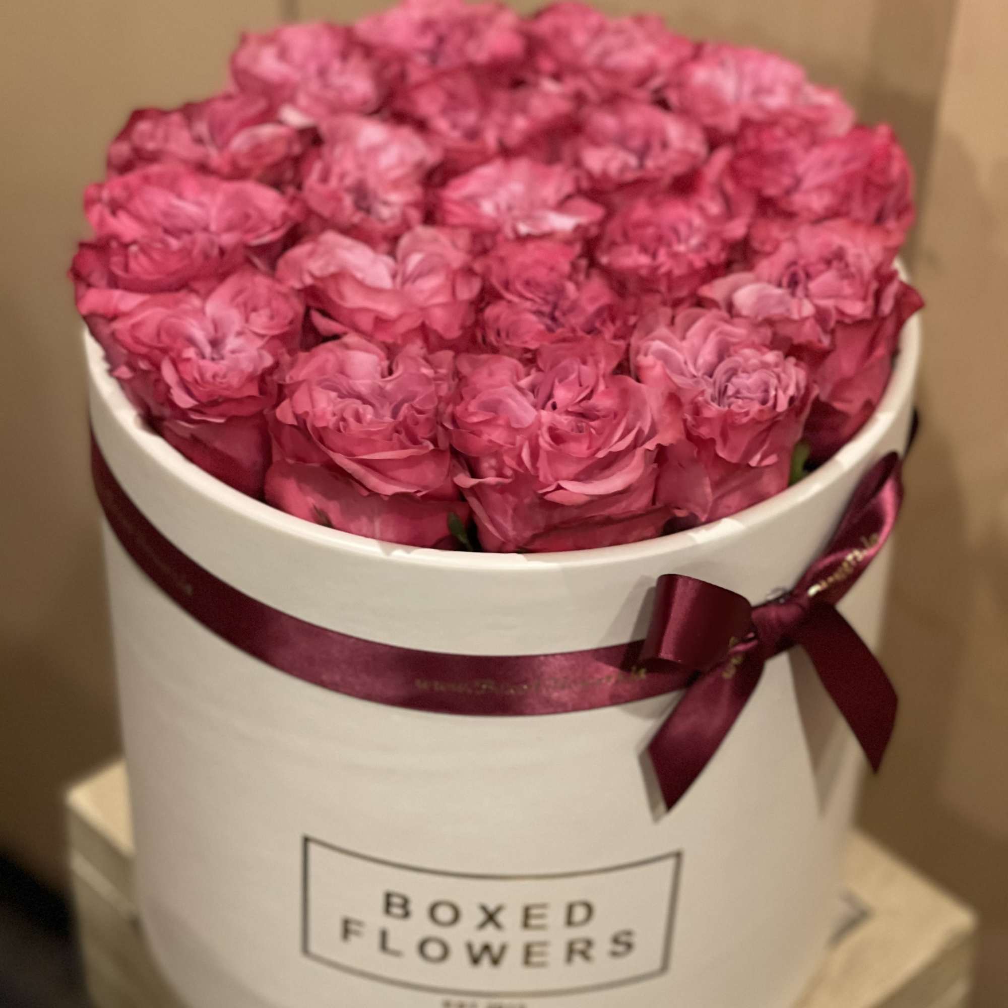 Pink roses arranged in a white hat box with a ribbon