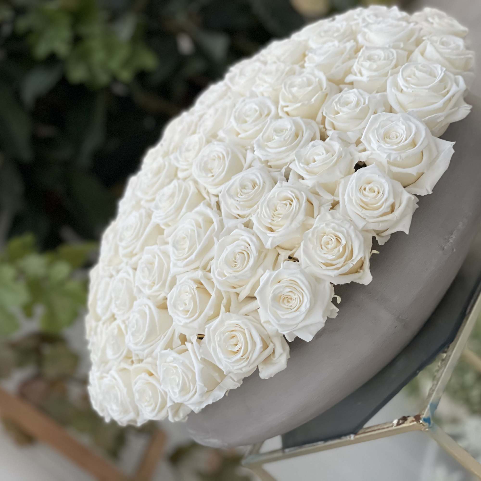 Round arrangement of white roses on a gray stand