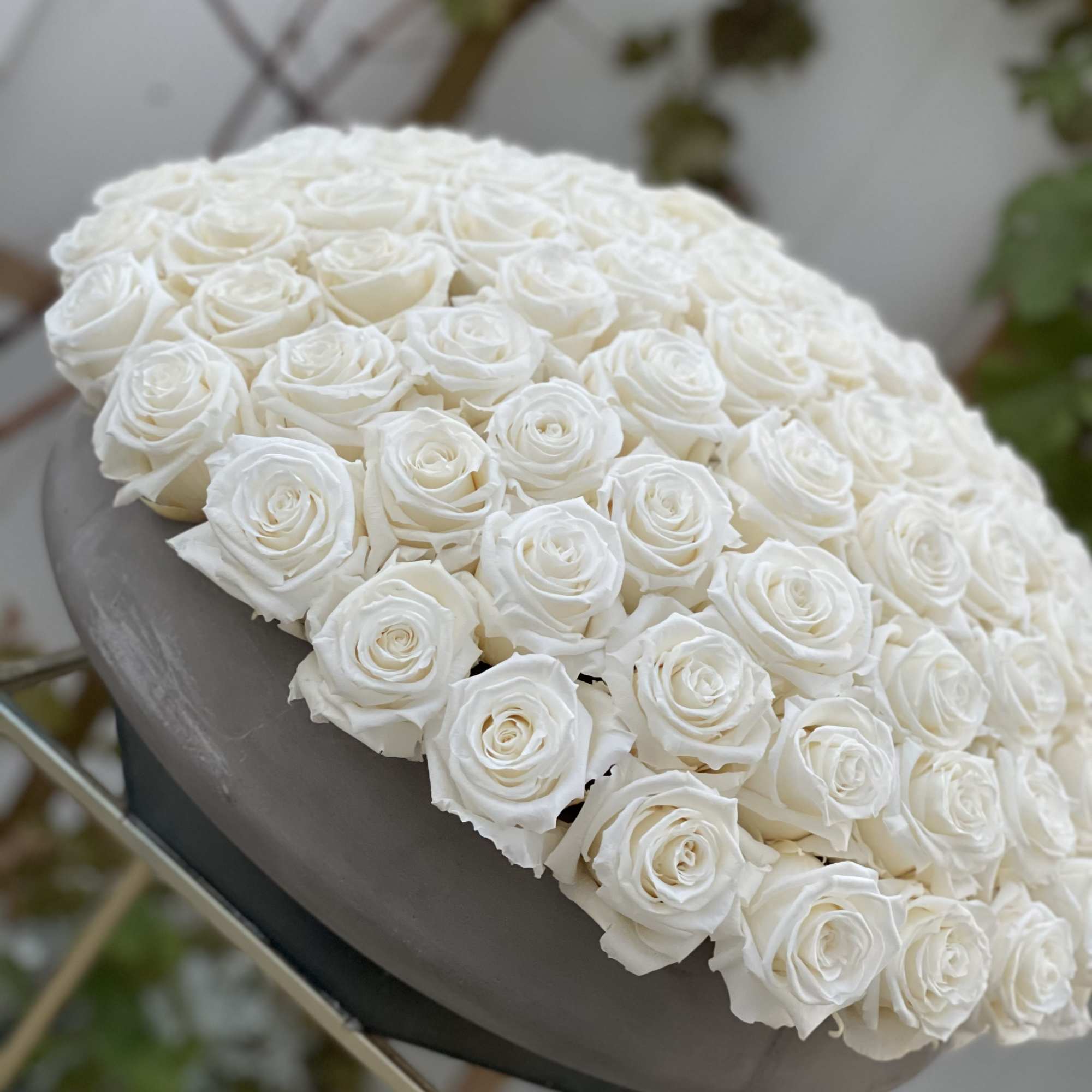 Large dome arrangement of white roses on a gray pedestal