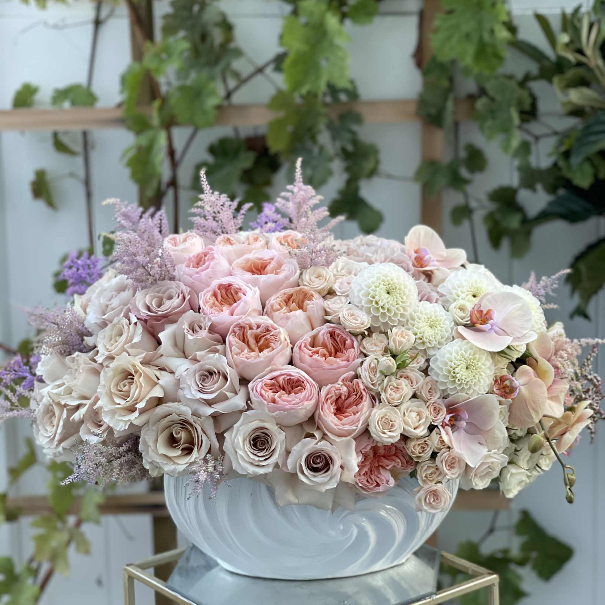 Large pastel flower arrangement in a white bowl vase