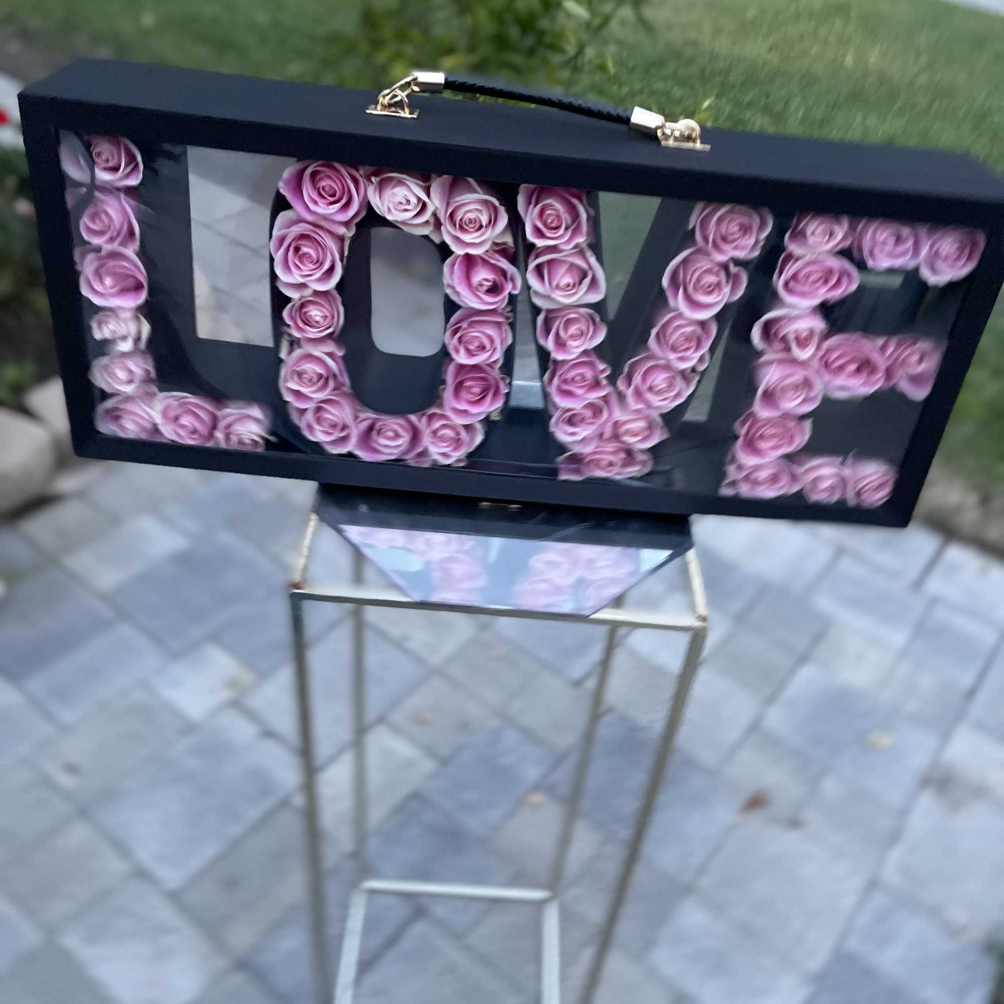 Pink roses arranged to spell LOVE in a black display case