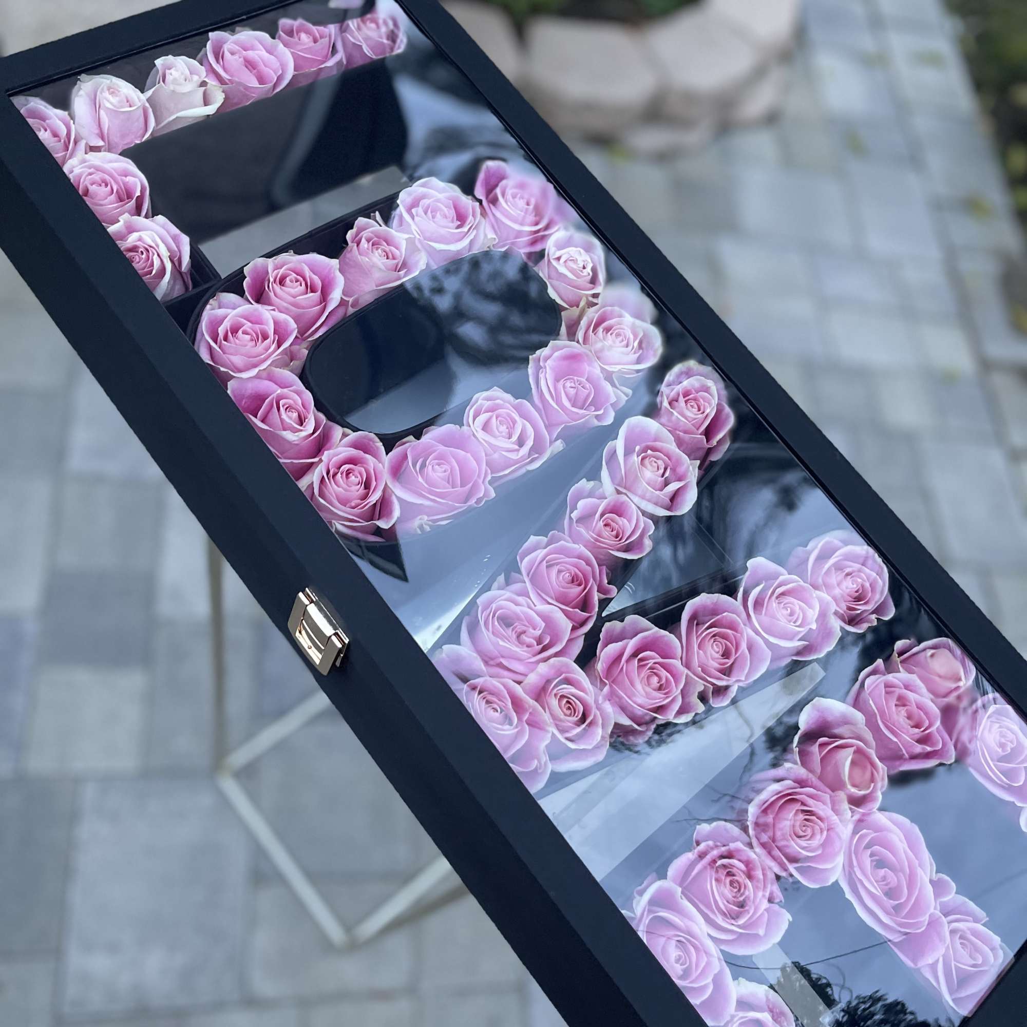 Pink roses arranged in a black box forming large letters