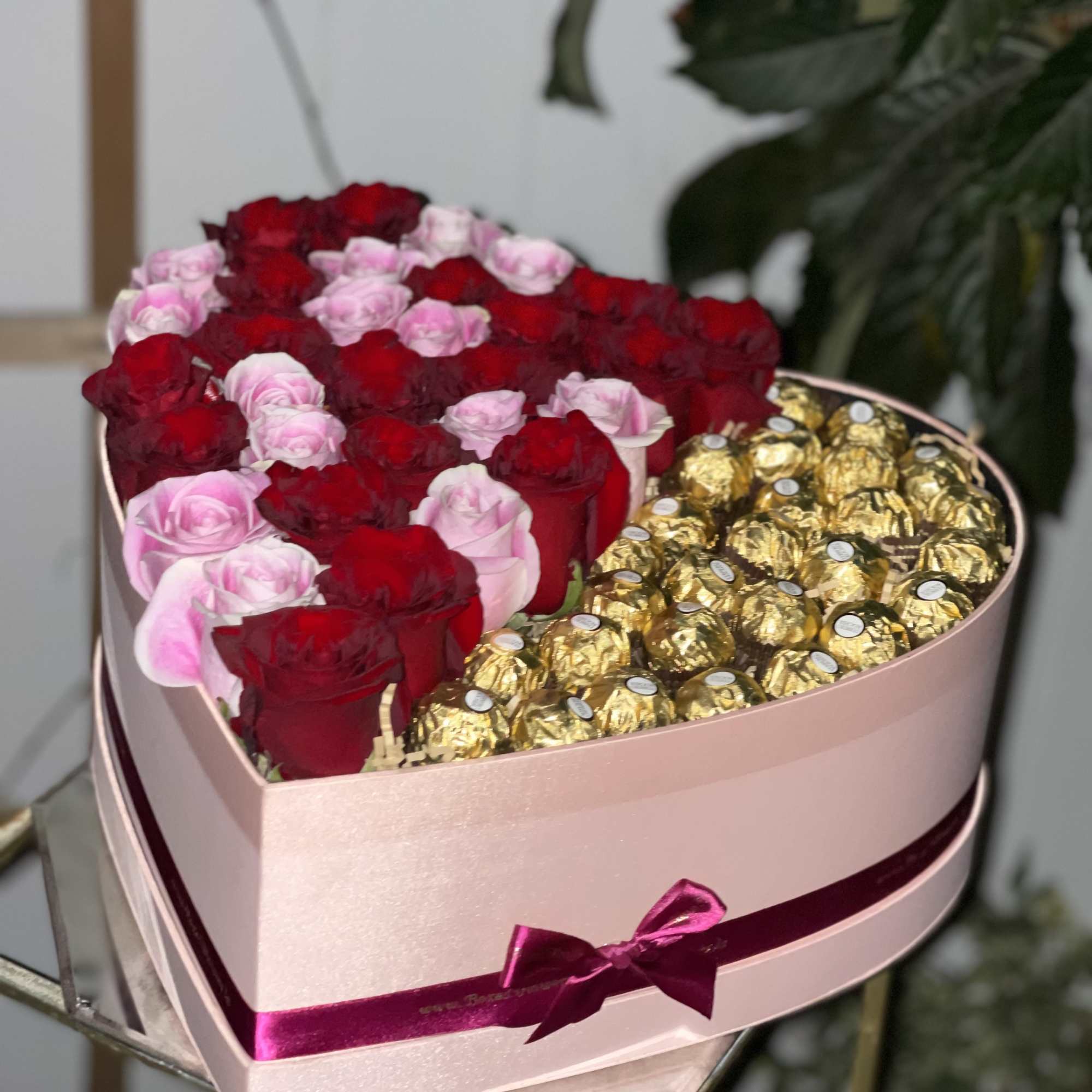 Heart-shaped box of red and pink roses with gold-wrapped chocolates