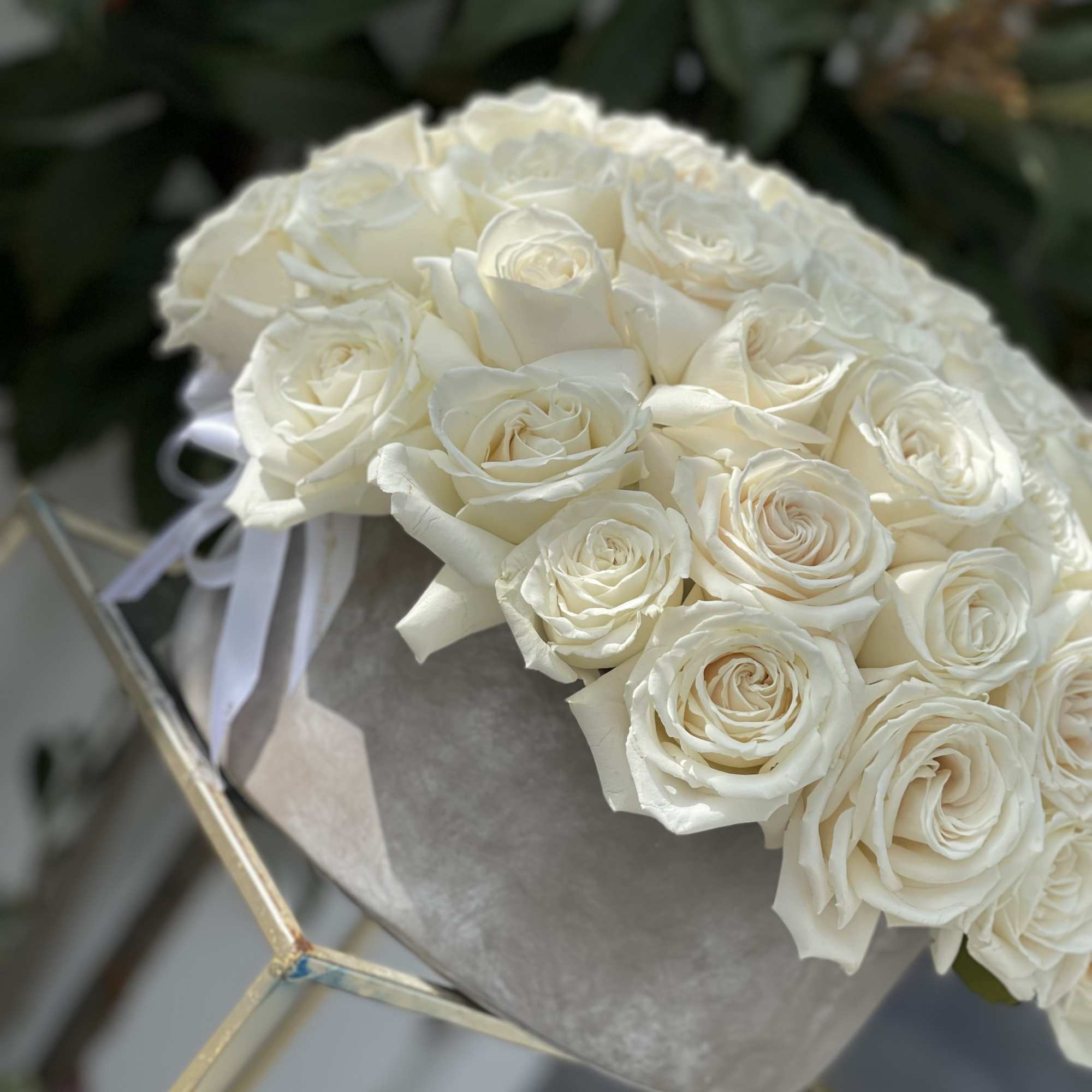 Bouquet of white roses wrapped in gray paper with a white ribbon